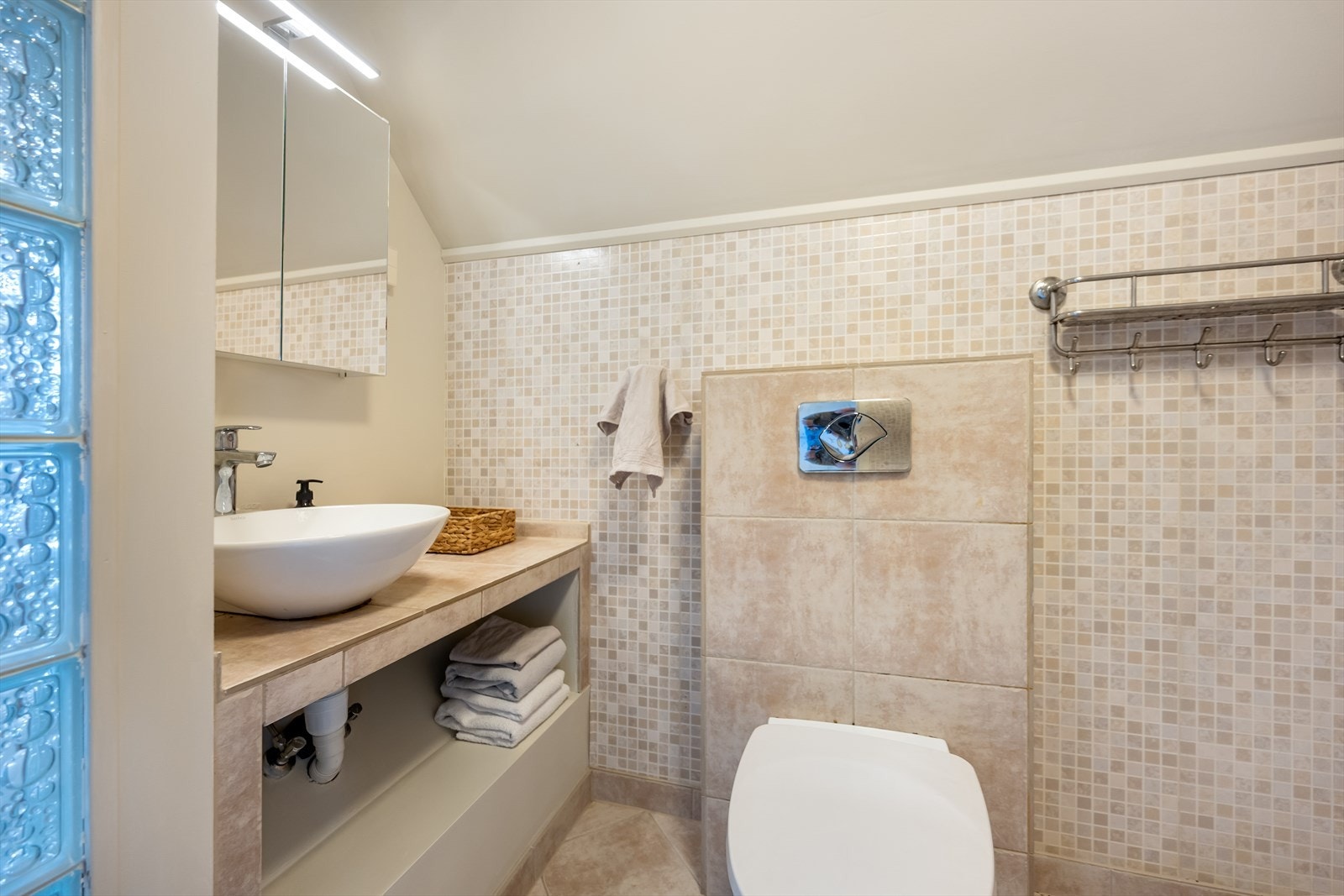 Badet er innredet med servantinnredning og veggmontert toalett. Galleribilde