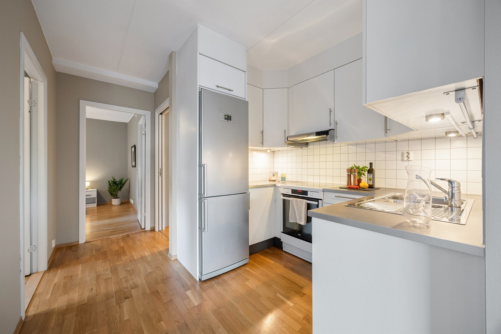 Stilrent kjøkken med hvite, glatte fronter og en solid laminat benkeplate. Galleribilde