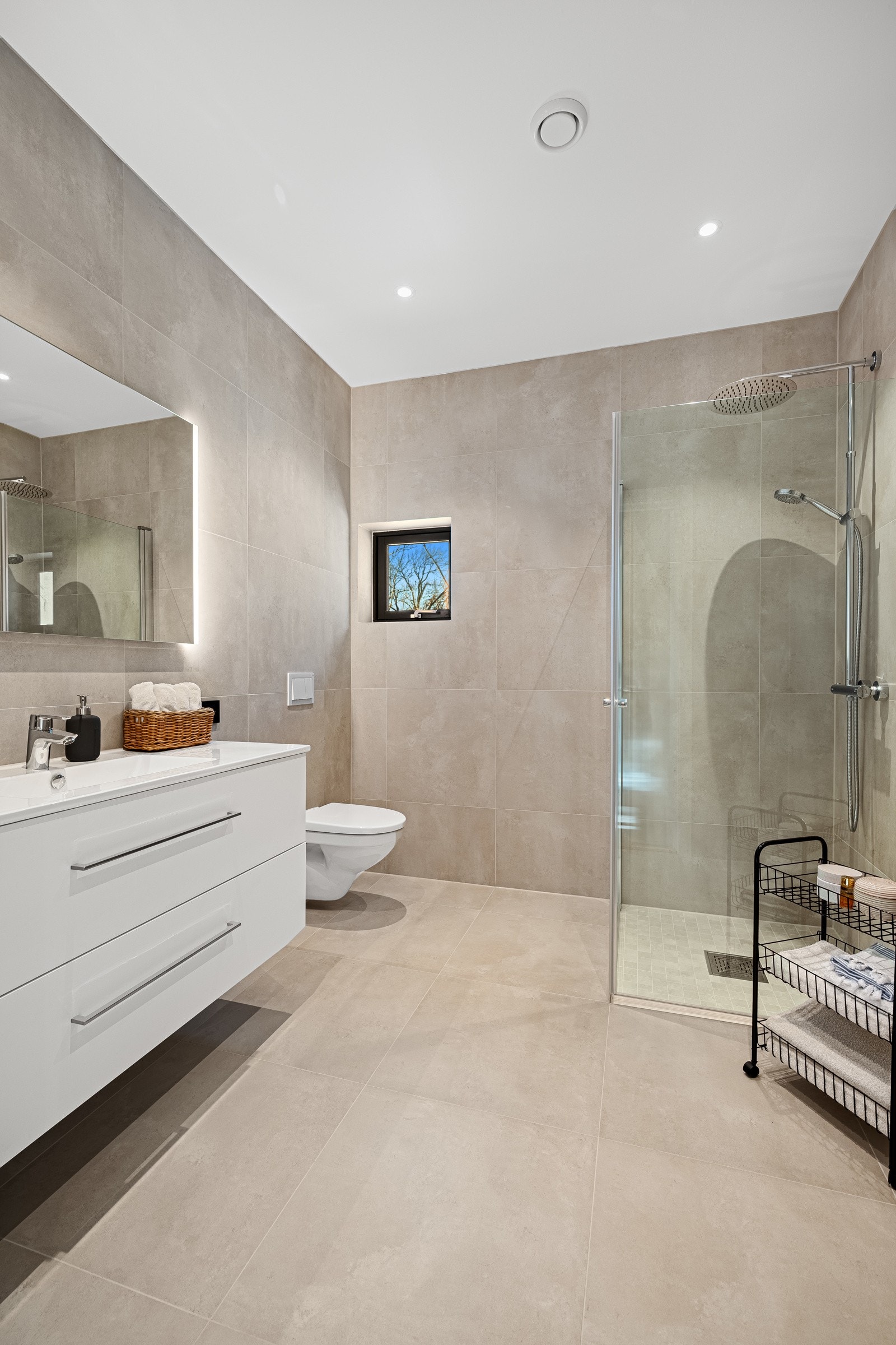 Badet er moderne og elegant, med store fliser på gulv og vegger som gir et tidløst preg. Her finner du alt du trenger for en god start på dagen. Galleribilde