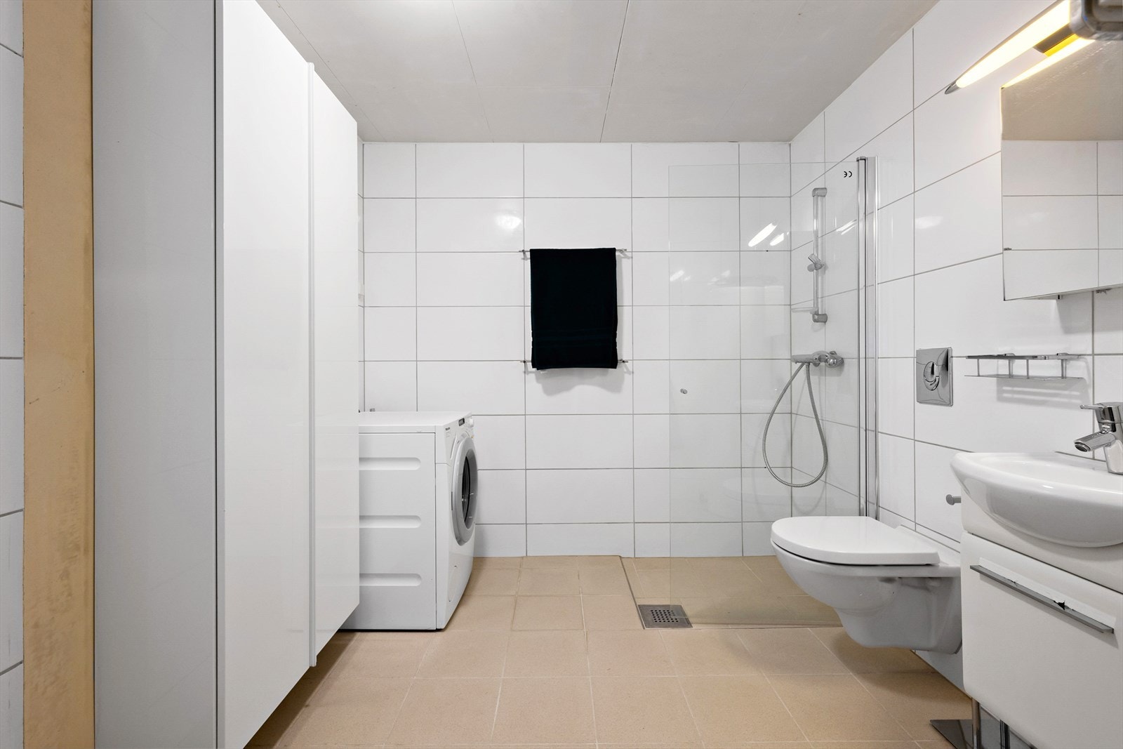 Lyst, flislagt bad med praktiske løsninger. Galleribilde