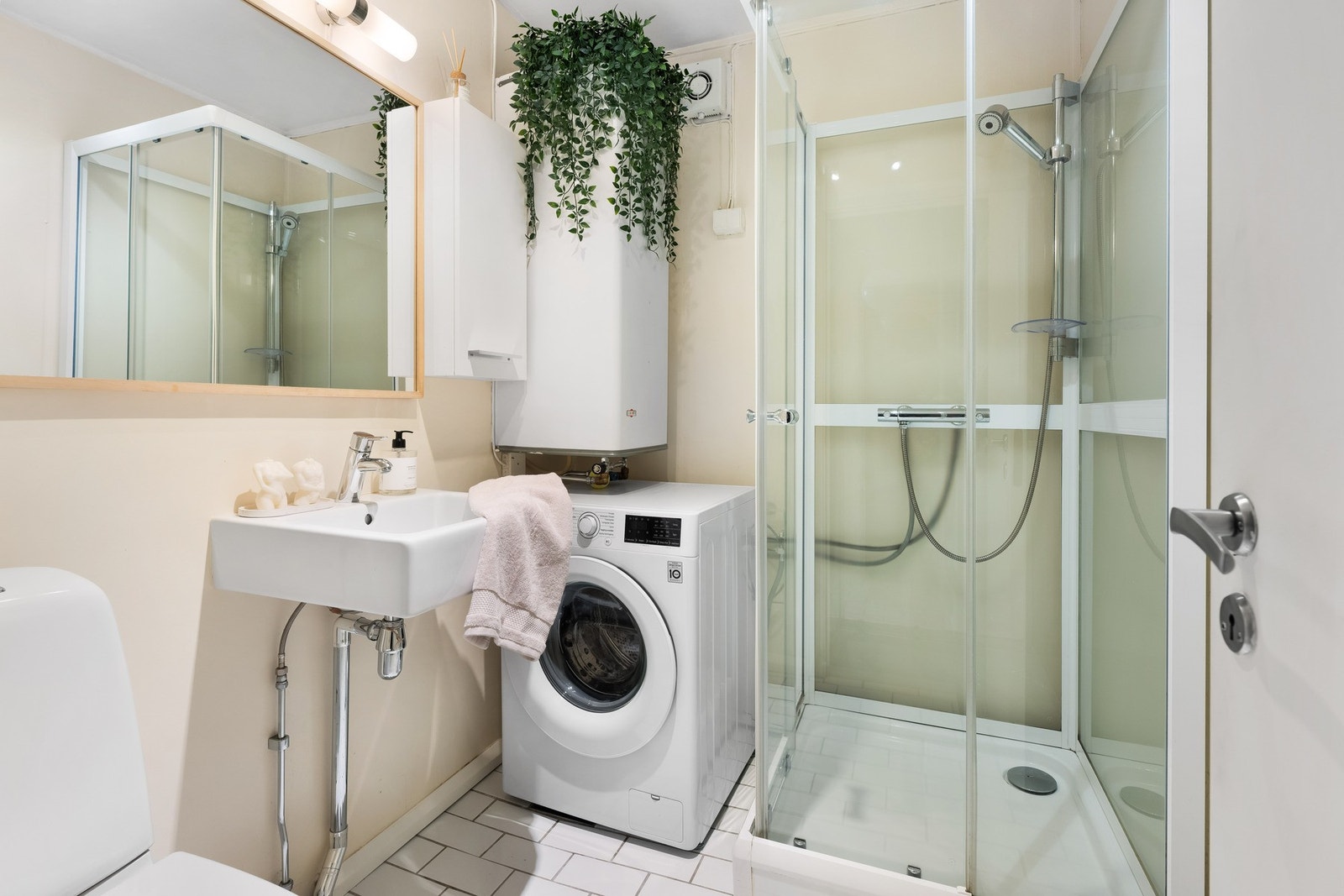 Badet inneholder toalett, helstøpt servant, dusjkabinett og opplegg for vaskemaskin. Galleribilde