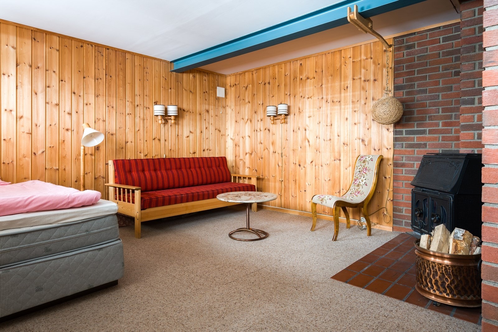 Kjellerstuen har panelvegger og teppebelagt gulv, med en vedovn som gir ekstra varme. Galleribilde