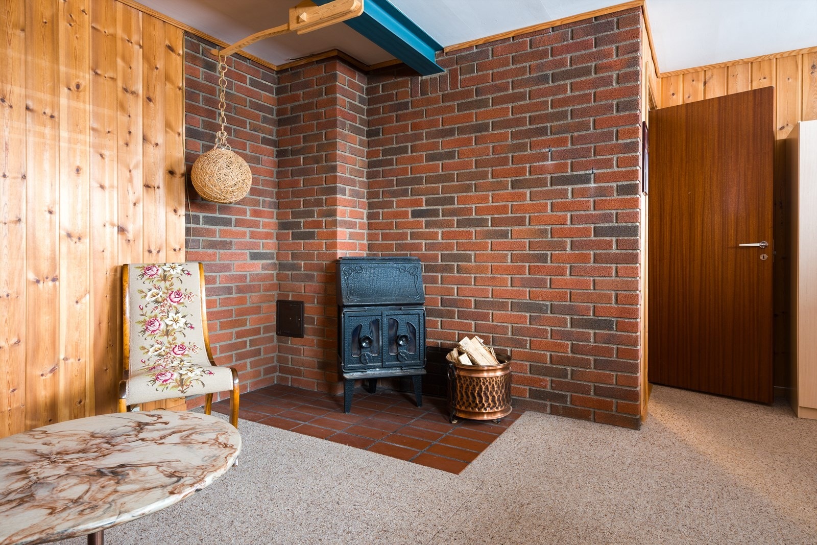 Mursteinsvegg med vedovn gir et rustikt preg i kjellerstuen, ideelt for kalde dager. Galleribilde