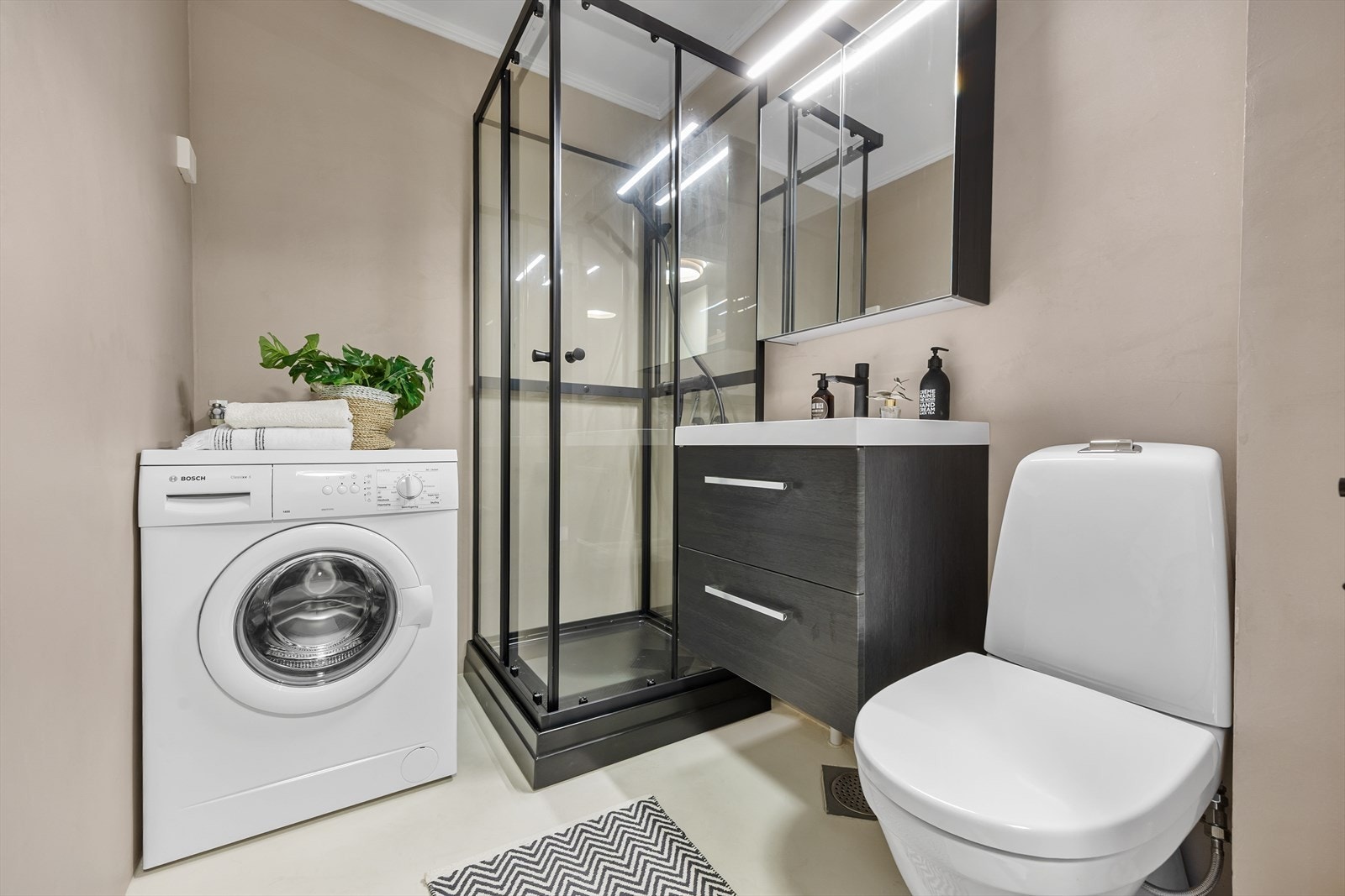 Badet har komfortabel gulvvarme, servant med skuffer, speilskap, dusjkabinett og opplegg for vaskemaskin. Galleribilde