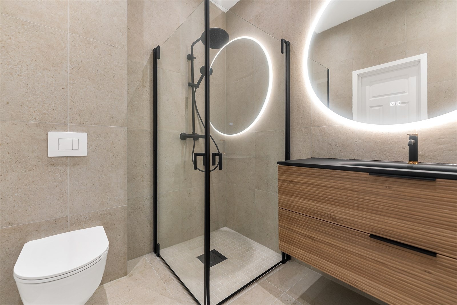 Moderne bad med dusjhjørne, vegghengt toalett og stilrent servantskap. Elegant belysning gir rommet et eksklusivt preg. Baderom nr. 2 Galleribilde