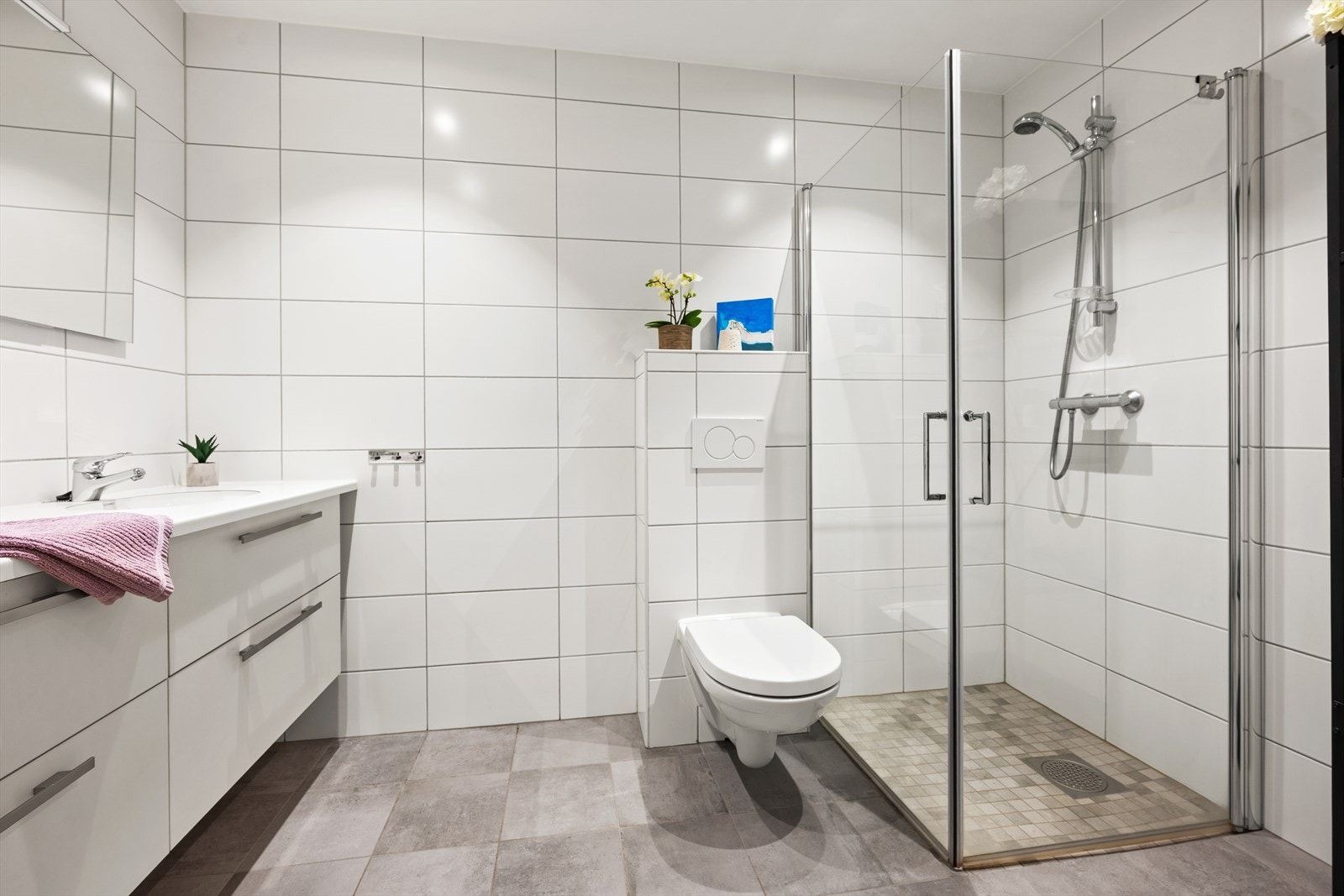 Badet er innredet med servant nedfelt i innredning med overskap og speil, dusjhjørne og vegghengt toalett Galleribilde