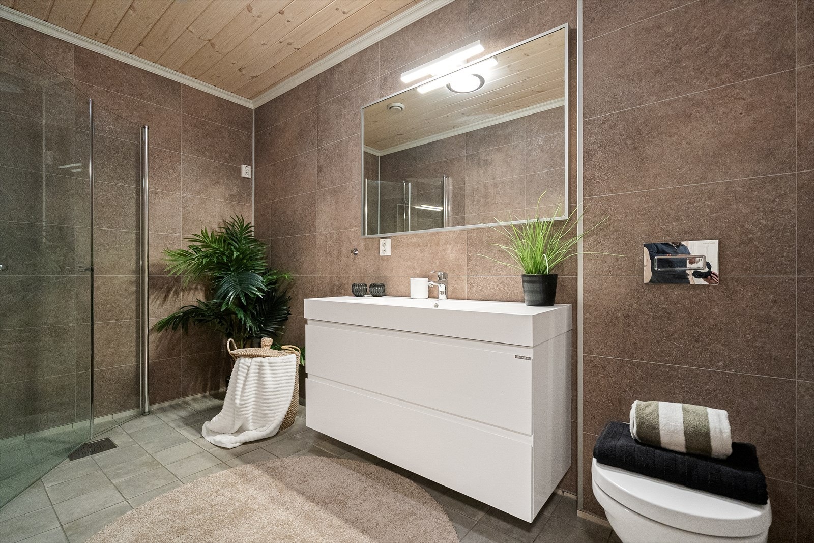 Heldekkende servant og veggmontert toalett med lekkasjesikring gir praktisk løsning. Galleribilde