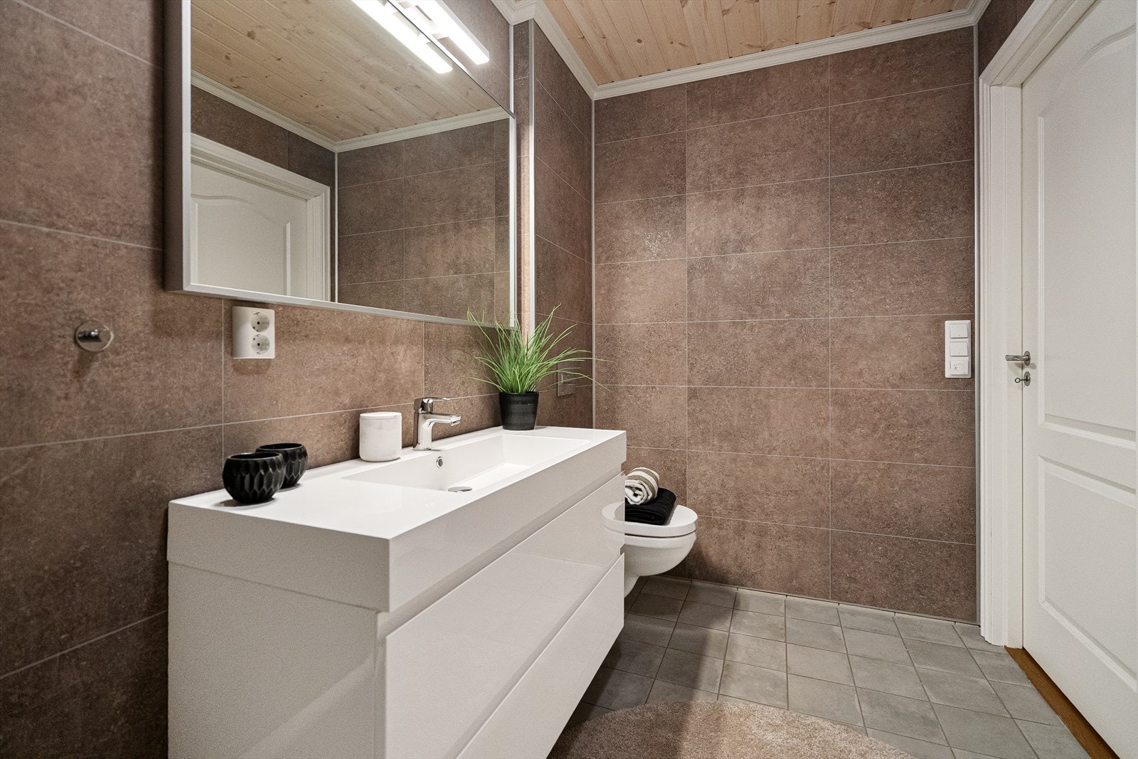 Veggene har baderomsplater og sokkelfliser, mens taket er kledd med lasert panel. Galleribilde