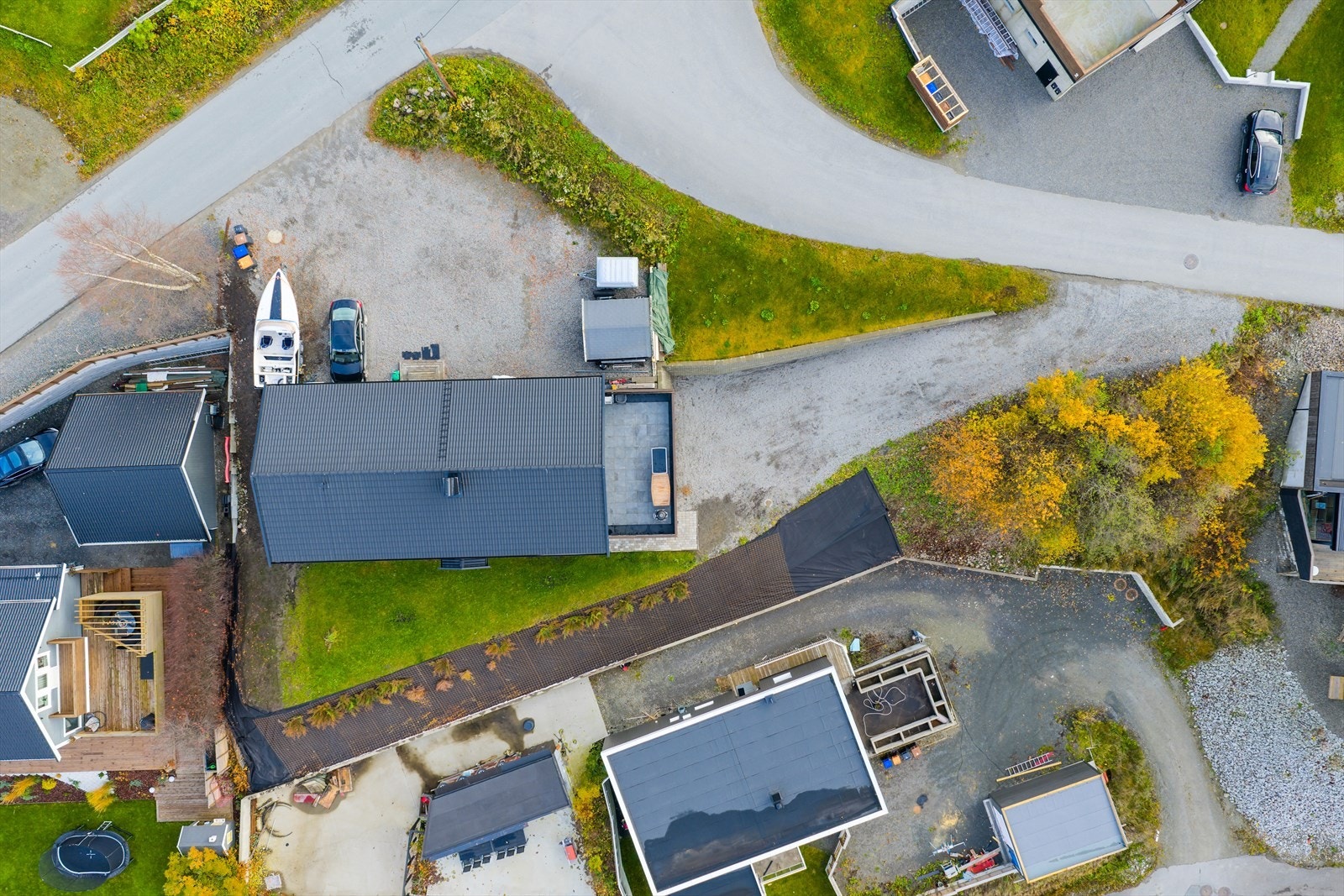Fra luftperspektiv sees eiendommens plassering med gruset innkjøring og parkeringsplass. Galleribilde