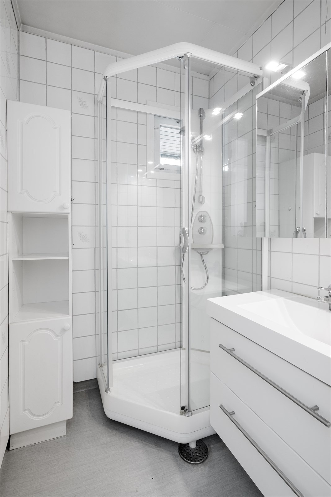 Lyst, eldre bad i hovedetasjen med belegg på gulv og flis på vegger. Badet har dusjkabinett og nyere servantinnredning, samt speilskap. Galleribilde