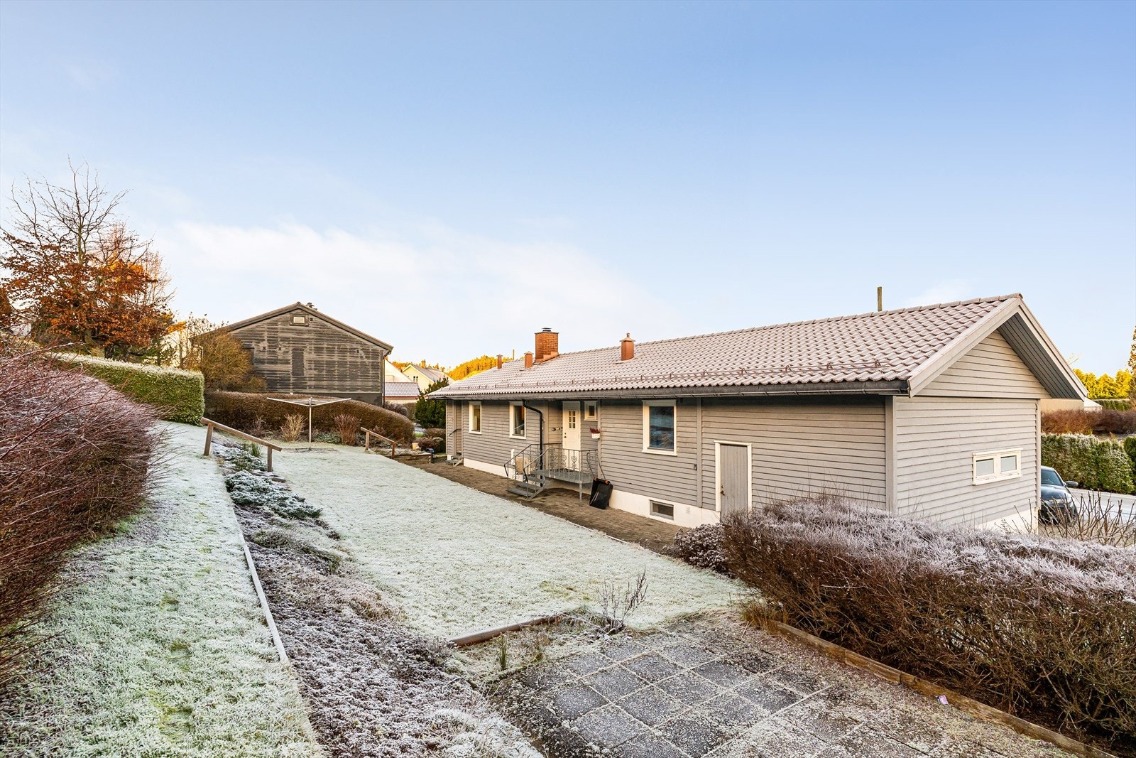 Romslig tomt i skrånende terreng, pent opparbeidet med plen, bed og diverse prydvekster, samt hekk langs tomtens grenser. Galleribilde