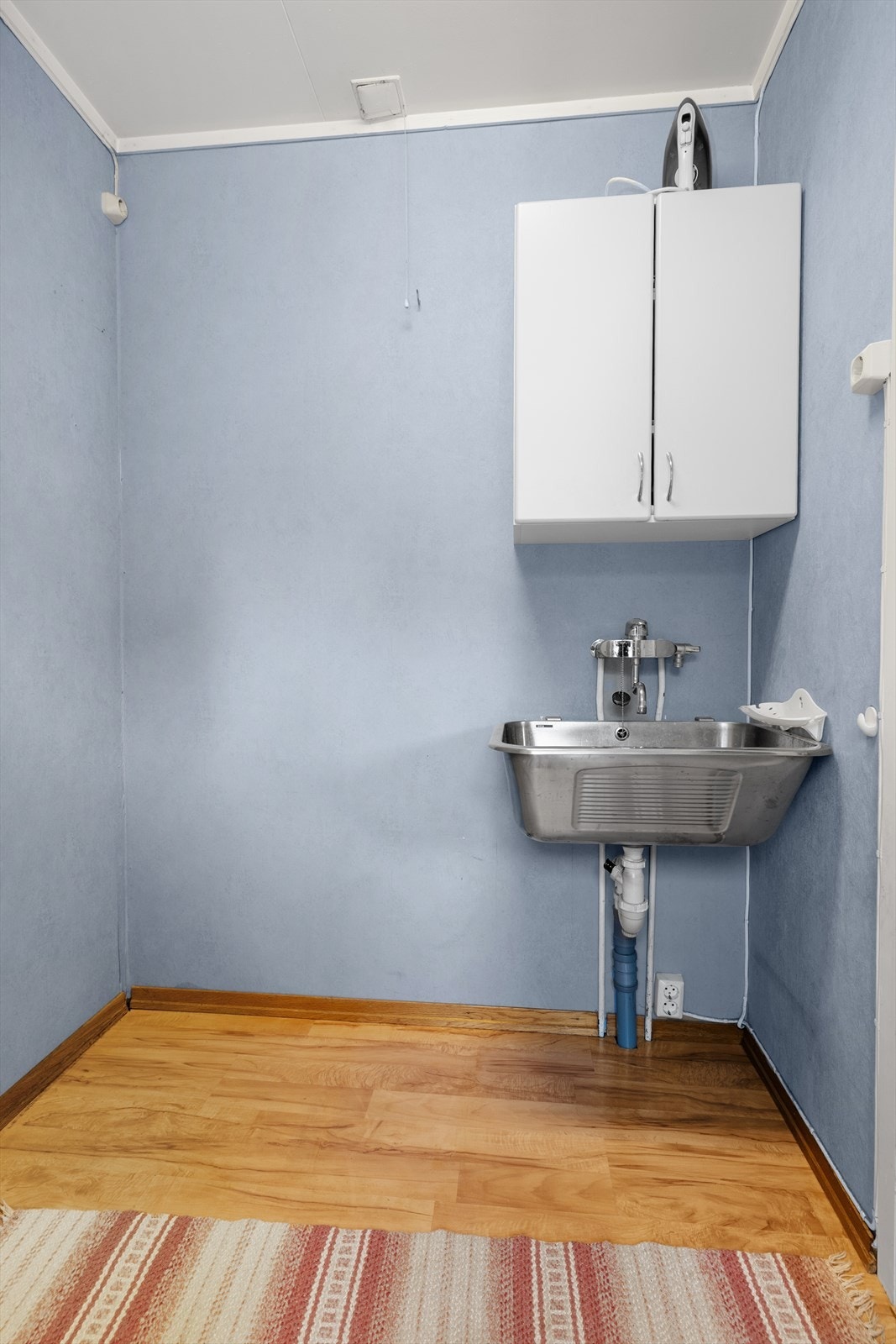 Arbeidsrom tilliggende kjøkkenet, utstyrt med utslagsvask og mulighet for tilkobling av vaskemaskin. Rommet mangler sluk. Galleribilde