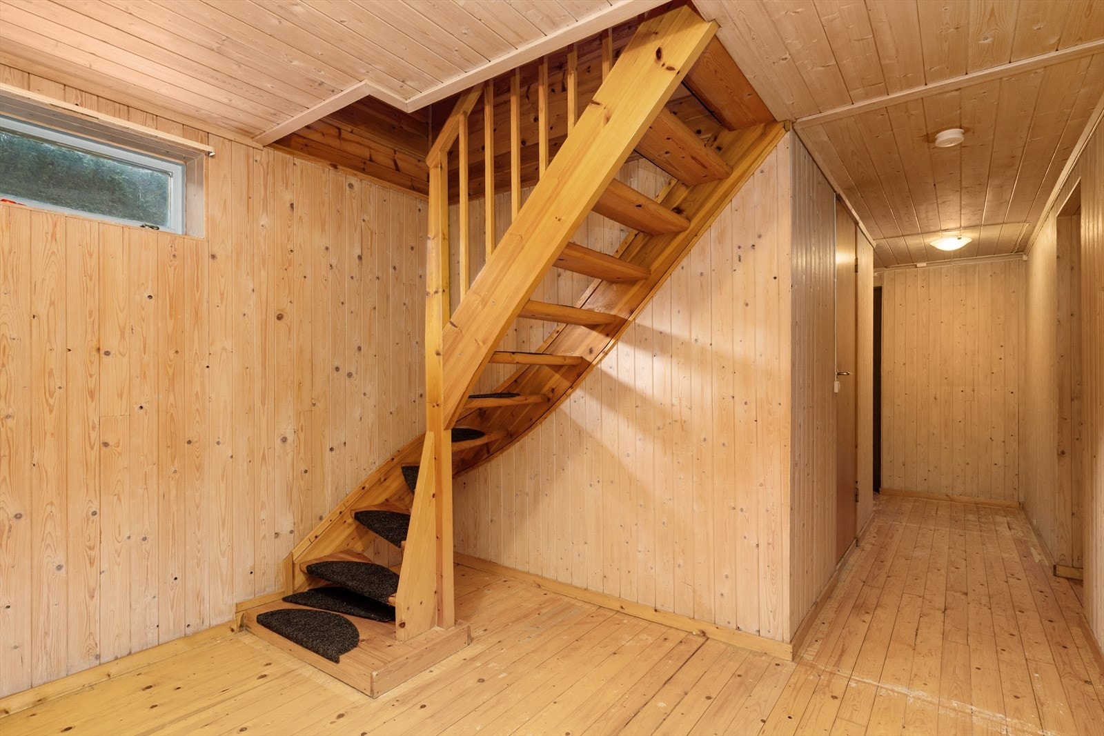 Boligen har en delvis innredet kjelleretasje, med innvendig adkomst via lakkert tretrapp mellom etasjene. Galleribilde