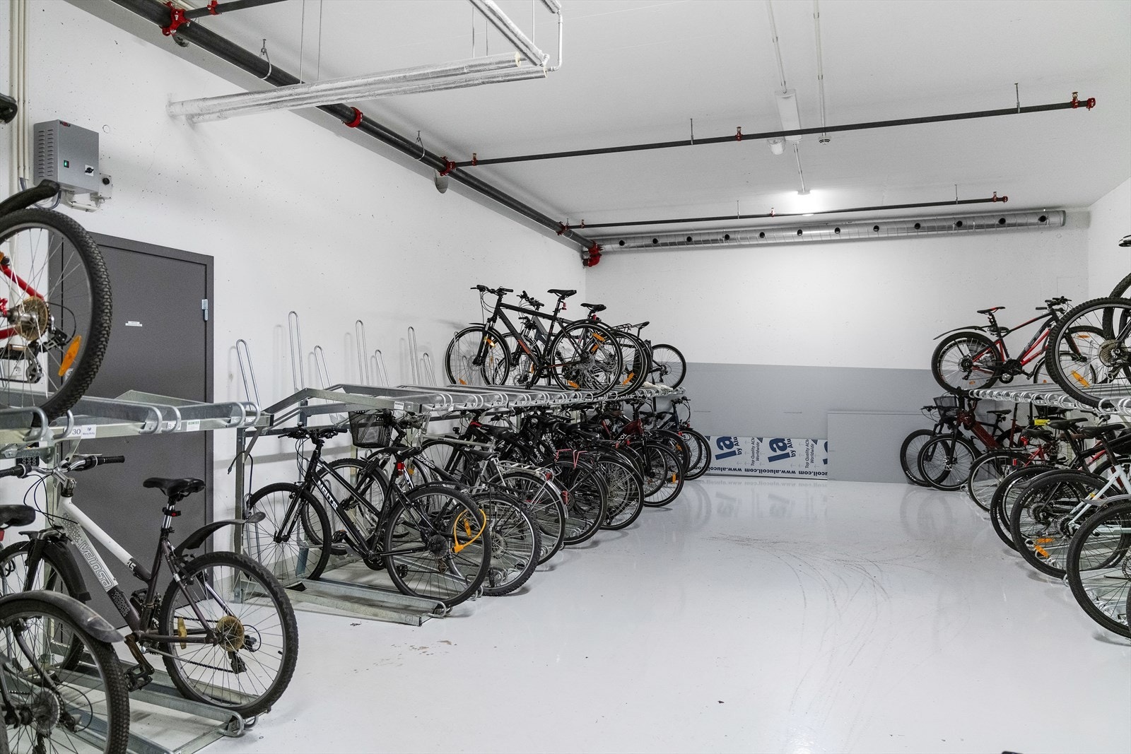 Felles, innendørs sykkelparkering i kjeller. Galleribilde