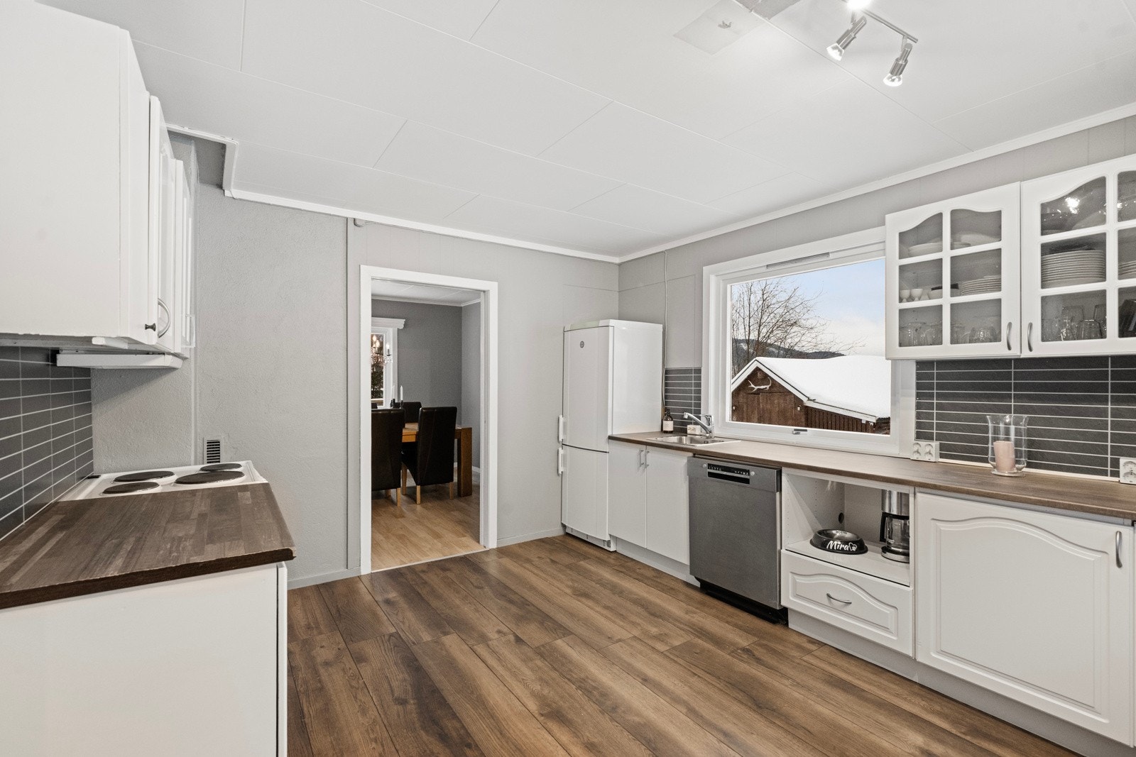 Kjøkkeninnredningen er fra 1990-tallet med under- og overskap med profilerte fronter, benkeplate med nedfelt vask og plass til oppvaskmaskin, komfyr og kjøleskap Galleribilde