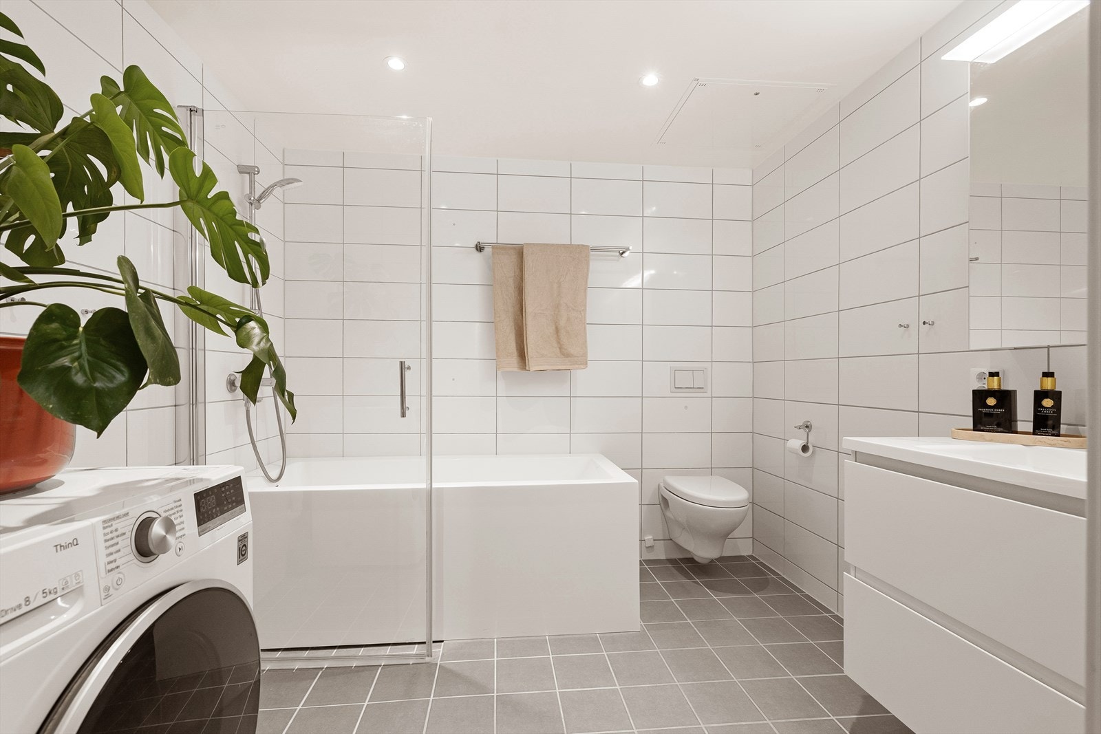 Pent bad med gulvvarme. Badet er utstyrt med badekar med tappekran og dusjslange, veggmontert toalett samt opplegg for vaskemaskin. Galleribilde