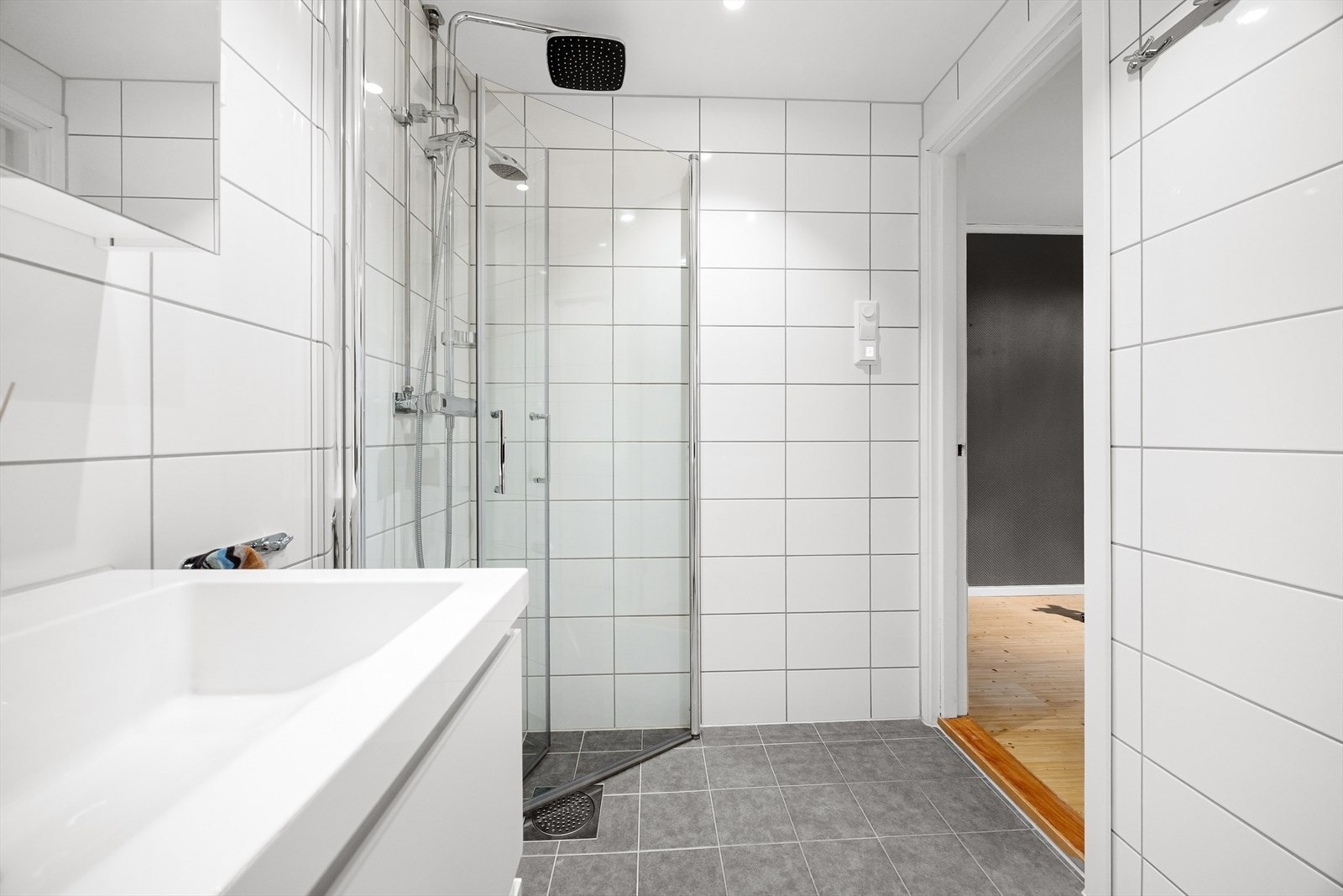 Baderommet inneholder dusjhjørne med innfellbare glassdører, servantskap og opplegg for vaskemaskin. Galleribilde