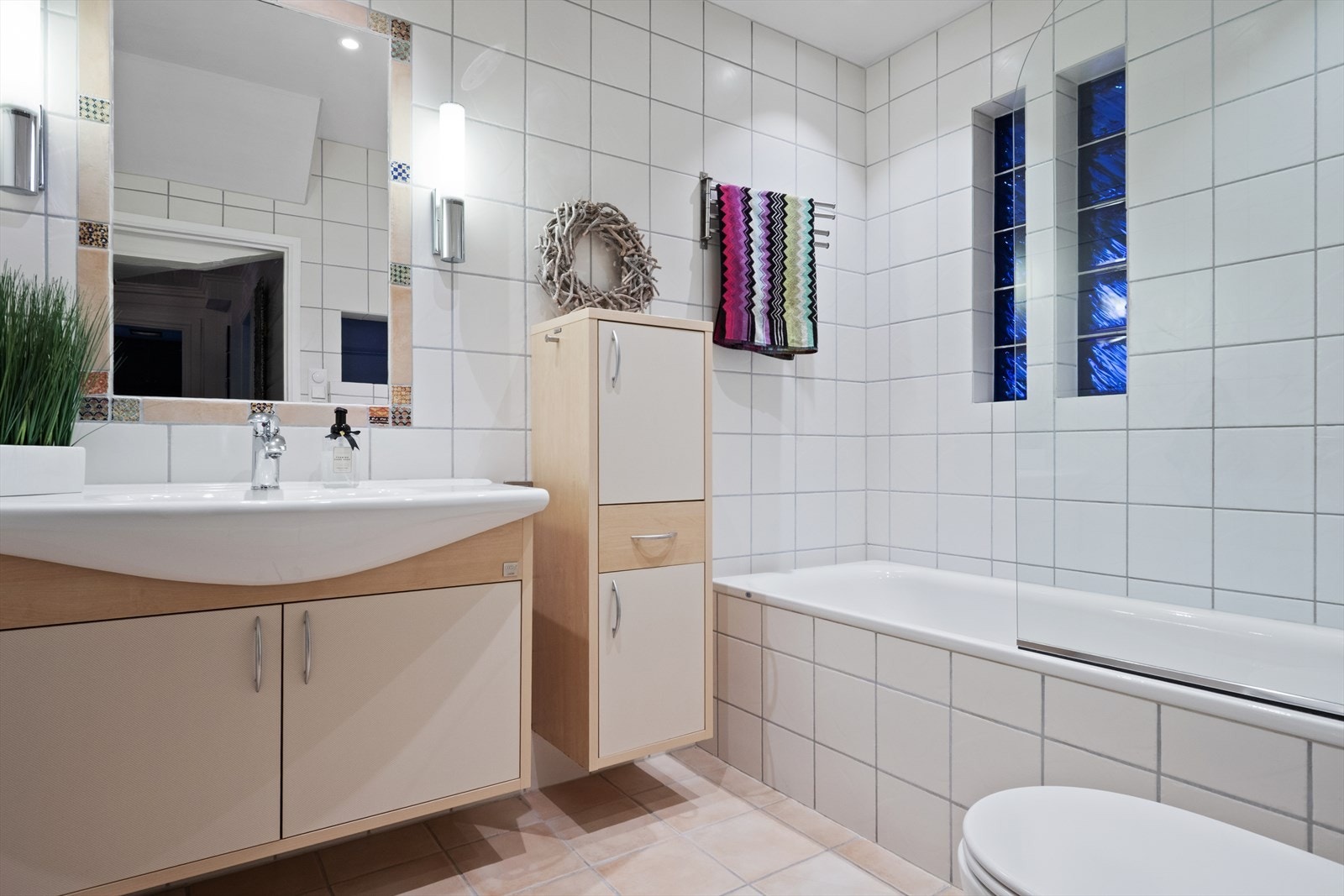 Badet i 1. etasjen har flislagte overflater, flislagt badekar, vegghengt toalett og servantinnredning. Galleribilde