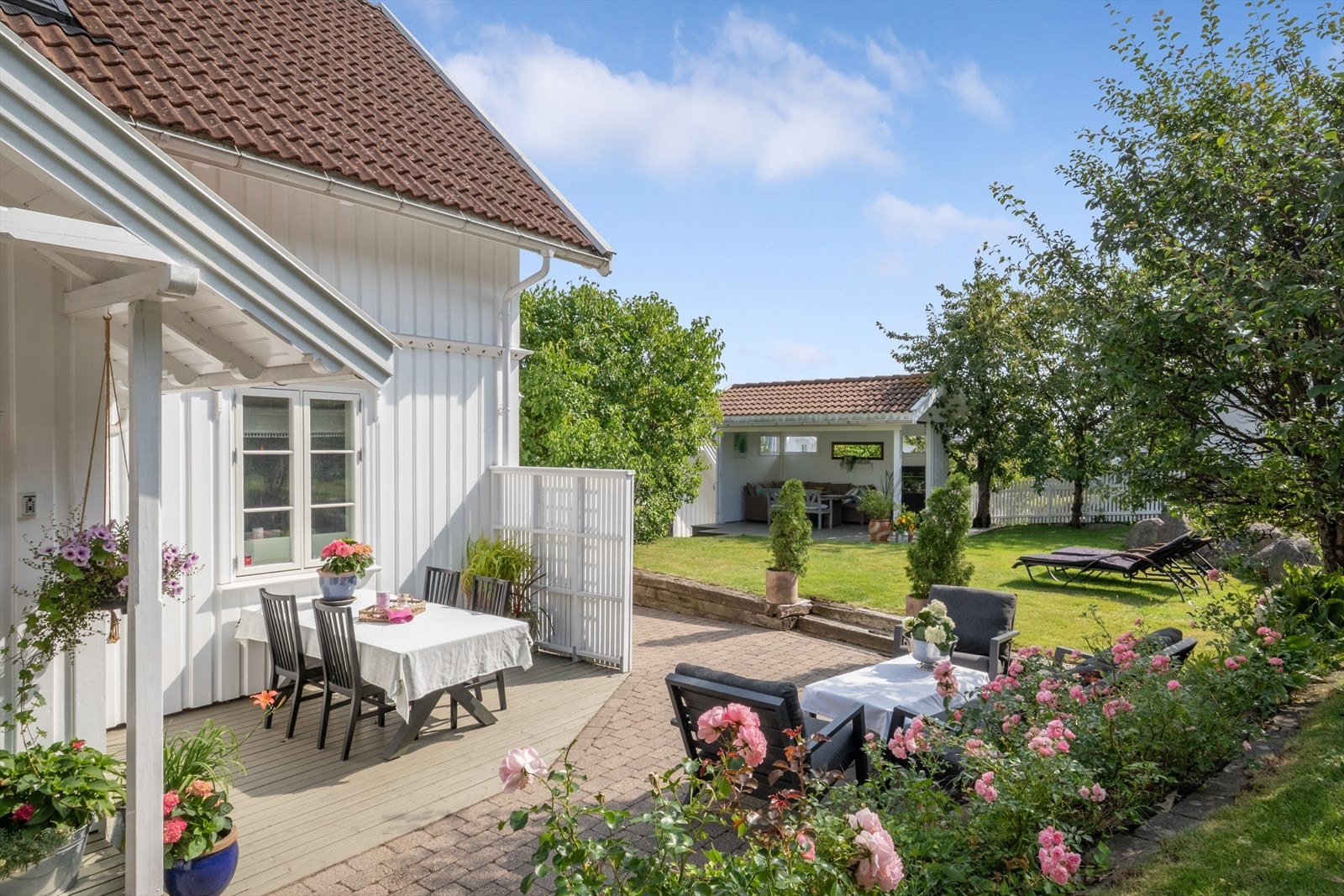 Eiendommen har romslige utearealer med terrasse og belegningsstein, omgitt av frodig beplantning. Galleribilde