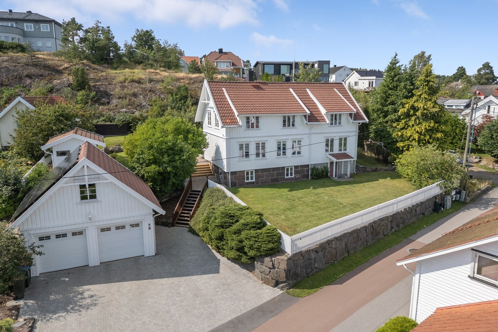 Huset ligger på en romslig tomt med plen og innrammet av hvitt stakittgjerde. Galleribilde