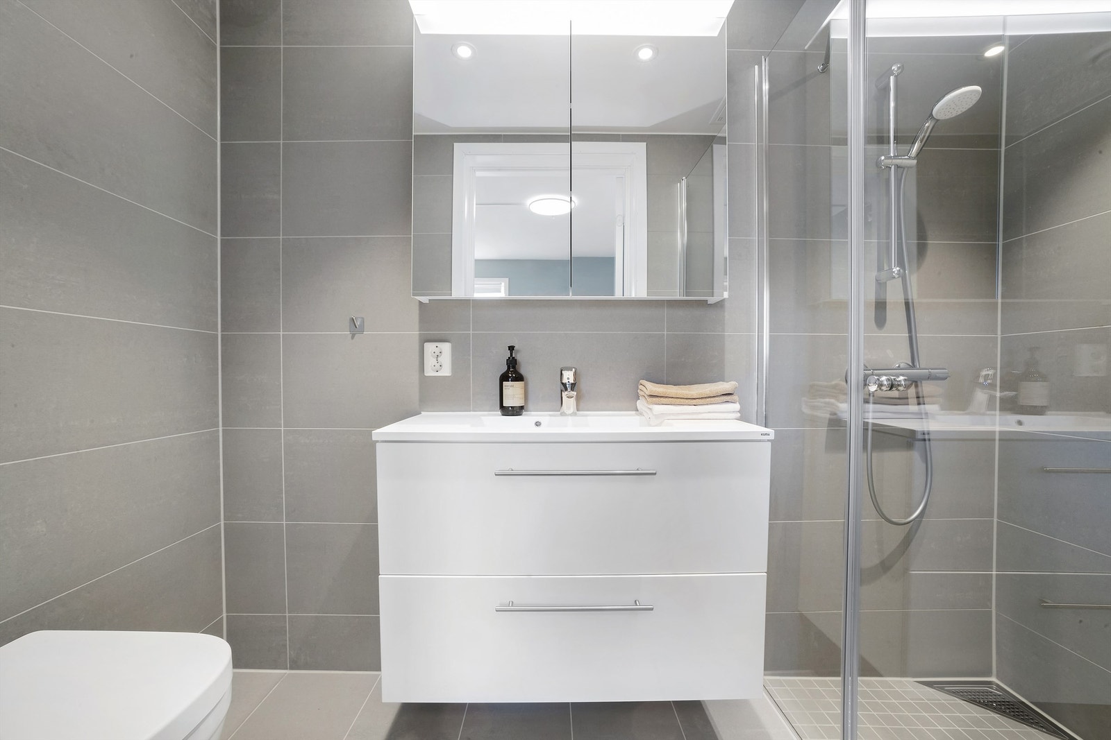 Badet fremstår lyst og moderne med hvite baderomsmøbler. Galleribilde