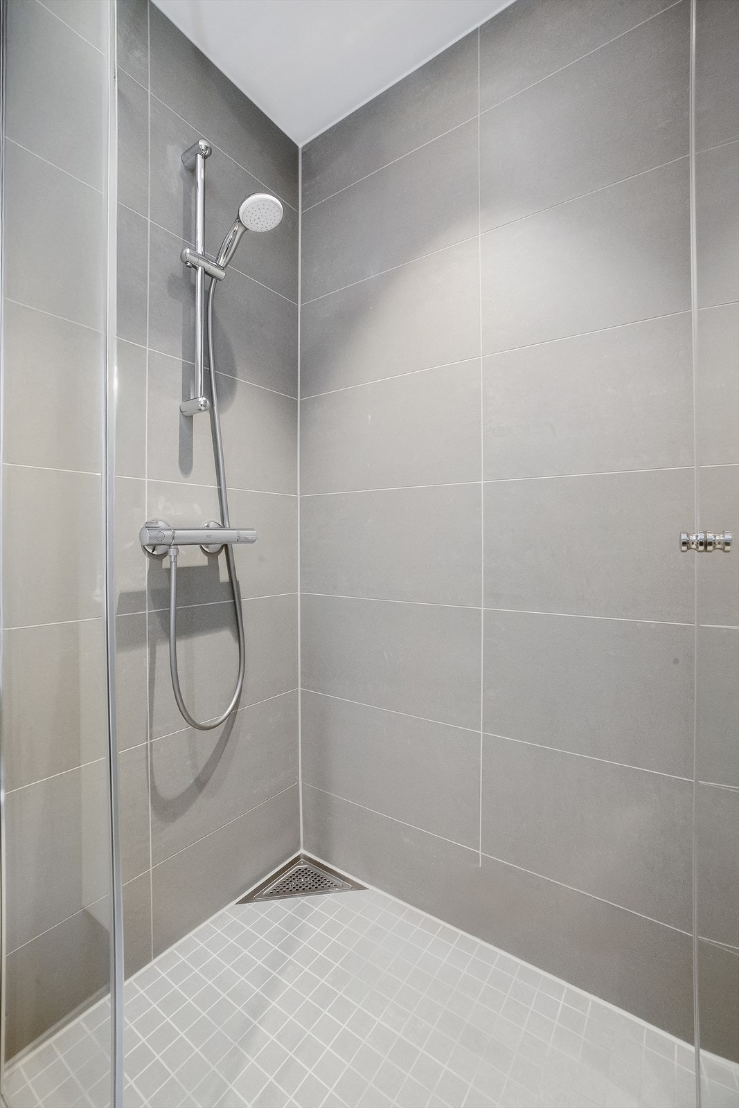 Romslig dusjnisje med etablert fallforhold og mosaikkfliser på gulvet. Galleribilde