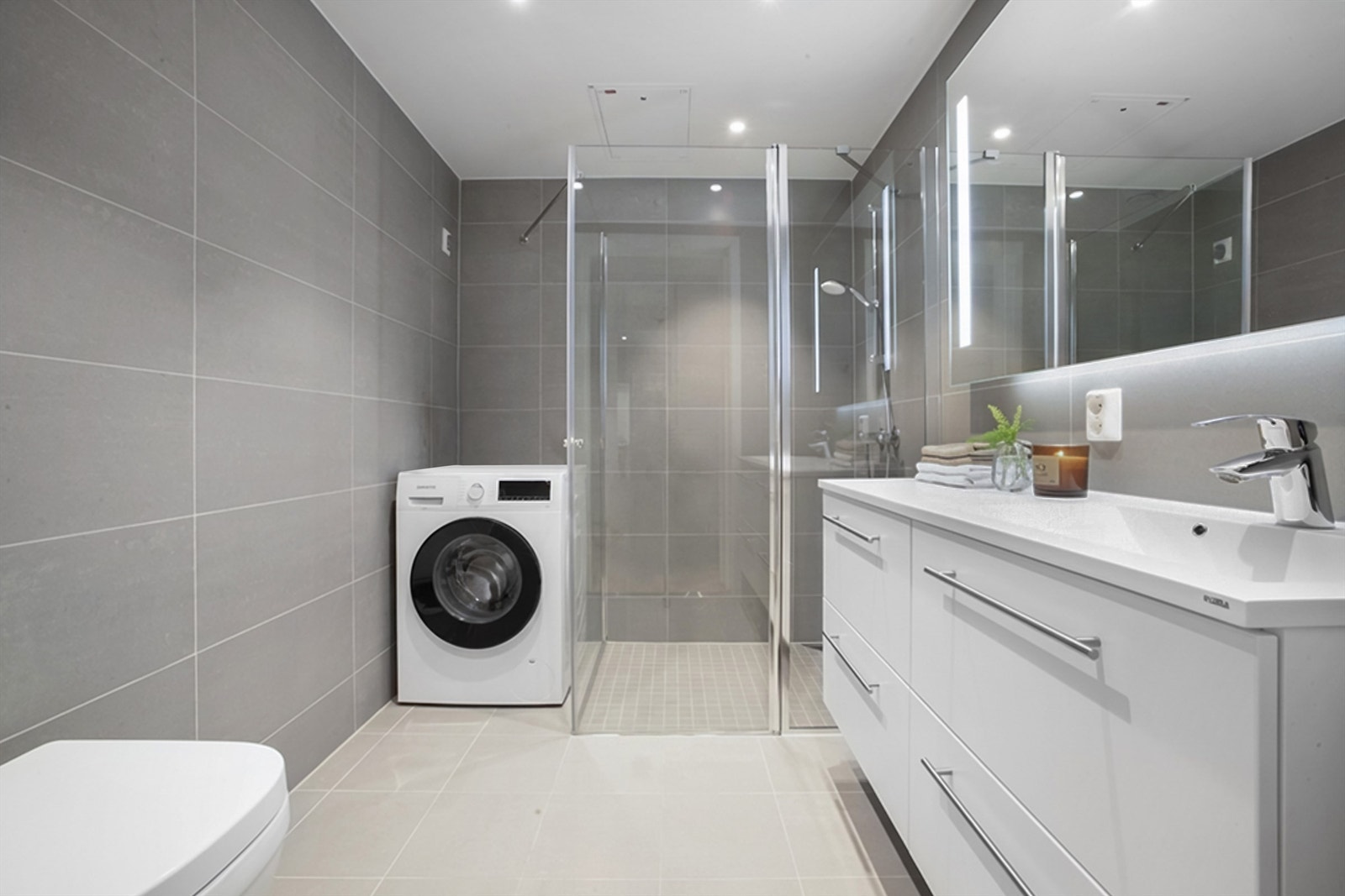 Badet er moderne med flislagte flater og varme i gulvet. Det er opplegg for vaskemaskin og tørketrommel. Galleribilde