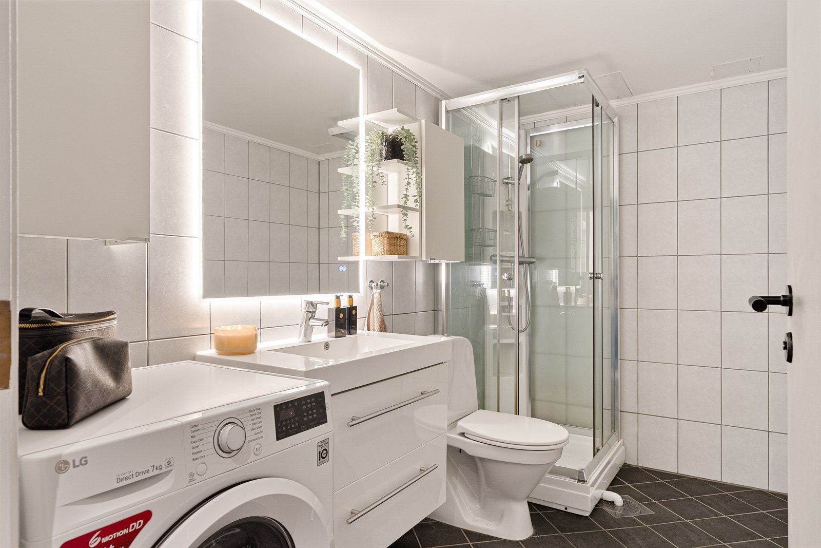 Flislagt bad på 4,8 m² utstyrt med ferdig opplegg for vaskemaskin, dusjkabinett, toalett og ny baderomsinnredning. Galleribilde