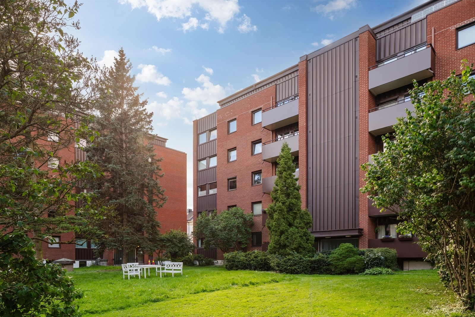 Felles hage med gressplen, beplantning og utemøbler. Gartner som har ansvaret for dette uteområde. Galleribilde