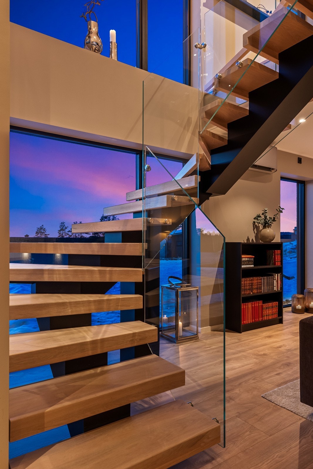 Trappen med eiketrinn og glassrekkverk leder elegant ned til 1. etasje. Galleribilde