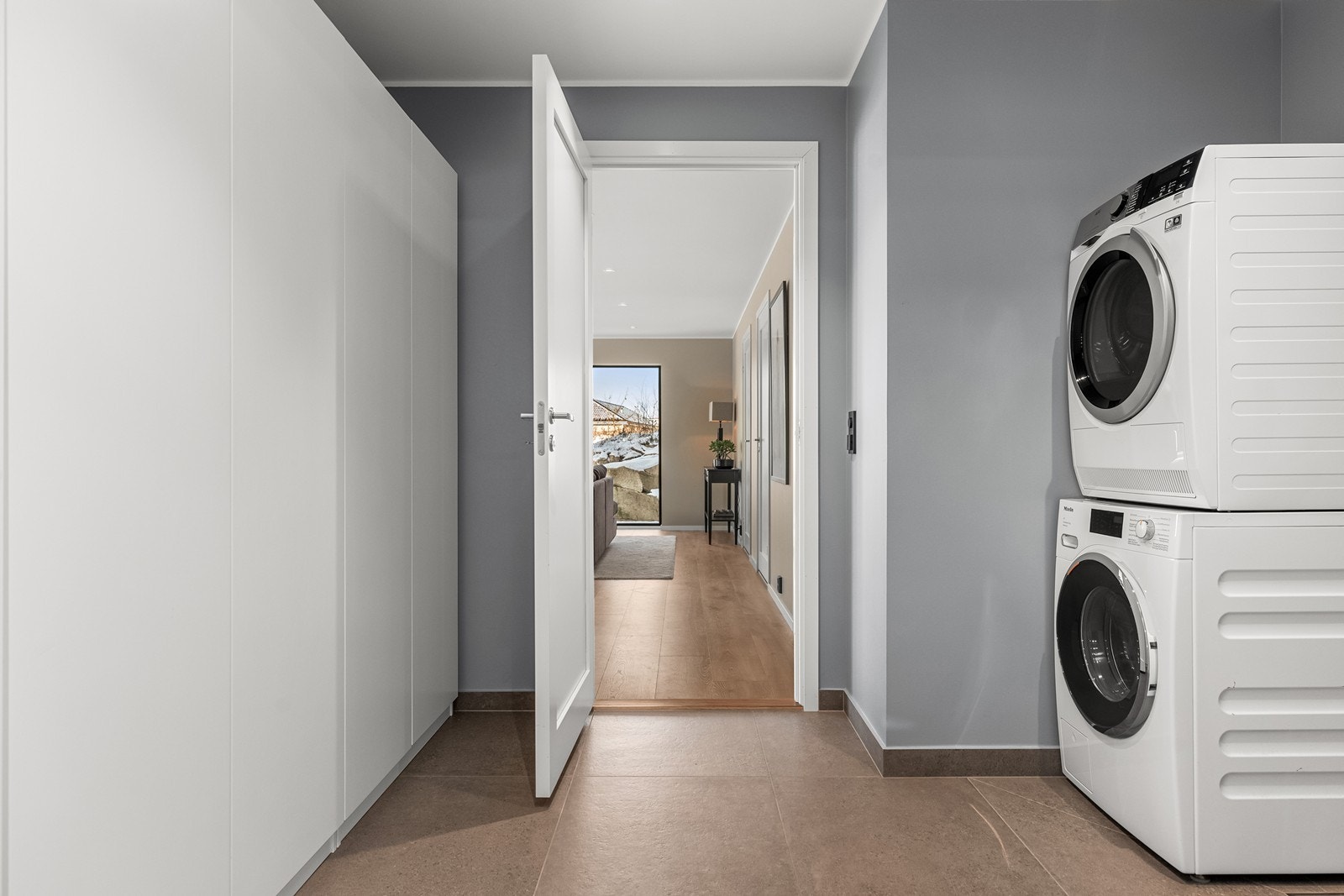 Praktisk og romslig vaskerom med opplegg for vaskesøyle og gode skapløsninger. Galleribilde