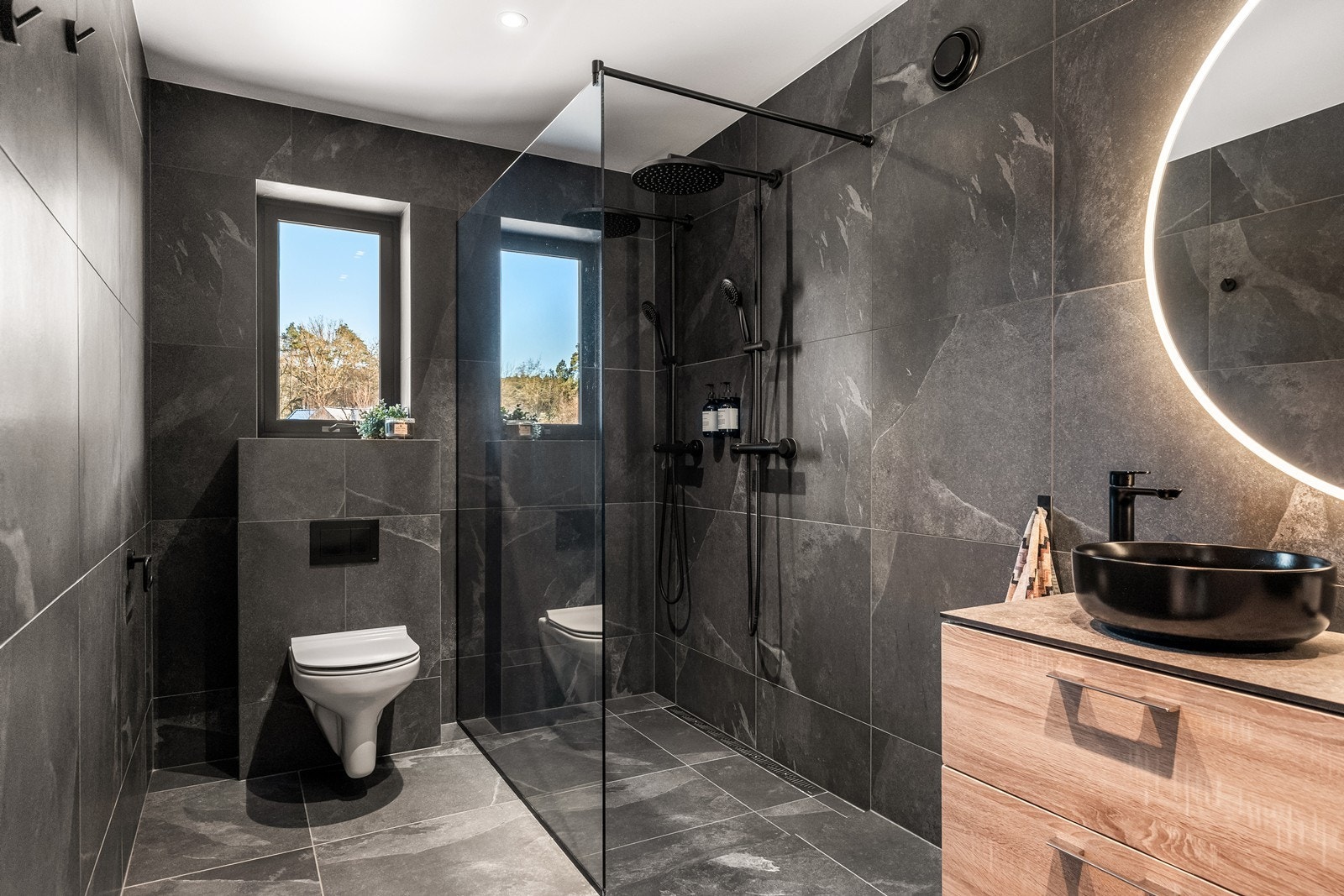 Hovedbadet er delikat utført med mørke fliser og en stor dusjsone. Galleribilde