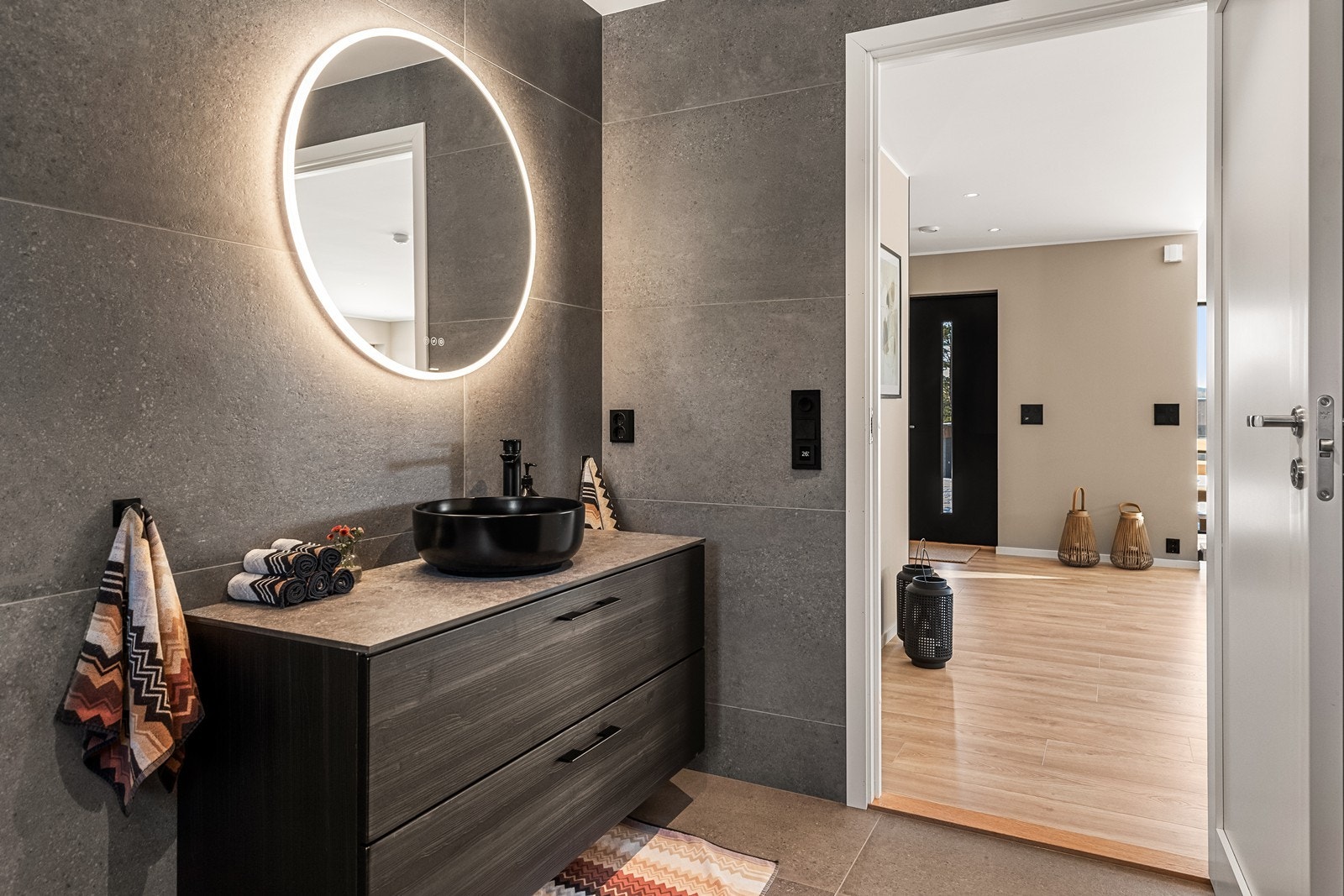 Baderomsinnredning med god oppbevaringsplass og et elegant, bakbelyst speil. Galleribilde