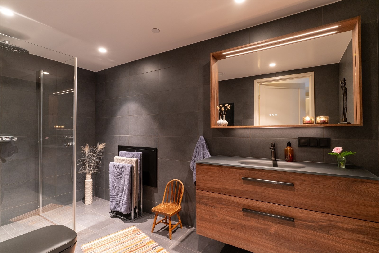 Boligens andre bad har mørke fliser og mørkt treverk, som gir en deilig og behagelig spafølelse. Galleribilde