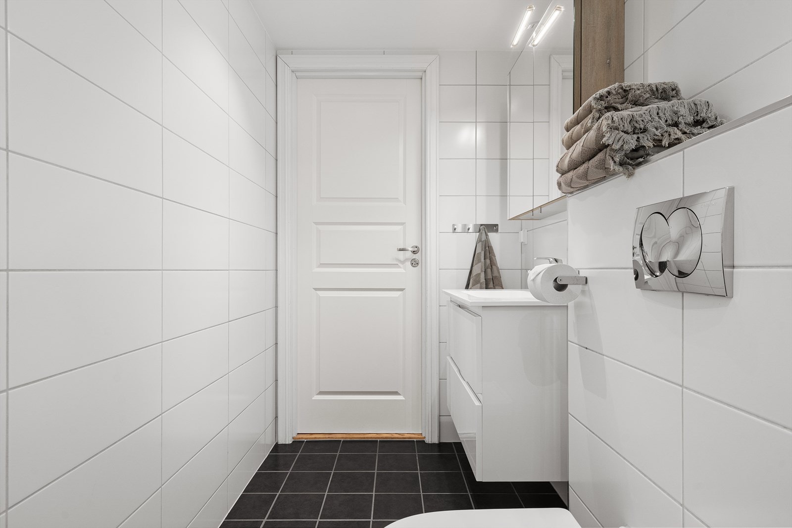 Badet er innredet med dusjhjørne, servant med innredning, speilskap med belysning og vegghengt toalett. Galleribilde