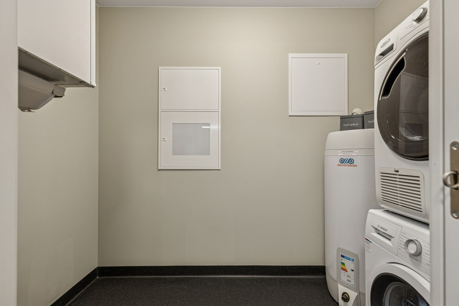 Vaskerommet er smart innredet med fliser på gulv, opplegg for vaskemaskin og god plass til oppbevaring. Galleribilde