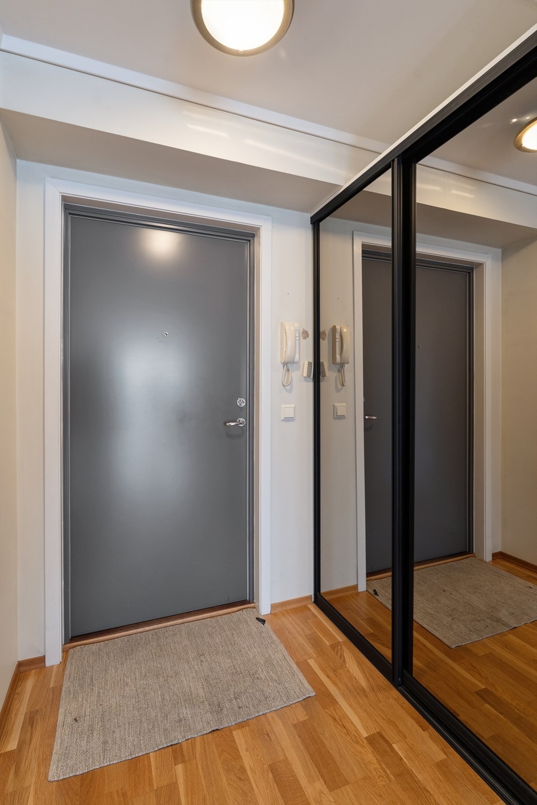 Entrèen med praktisk skyvedørsgarderobe. Speilfrontene skaper en ekstra god romfølelse. Dørtelefon er montert på veggen. Galleribilde