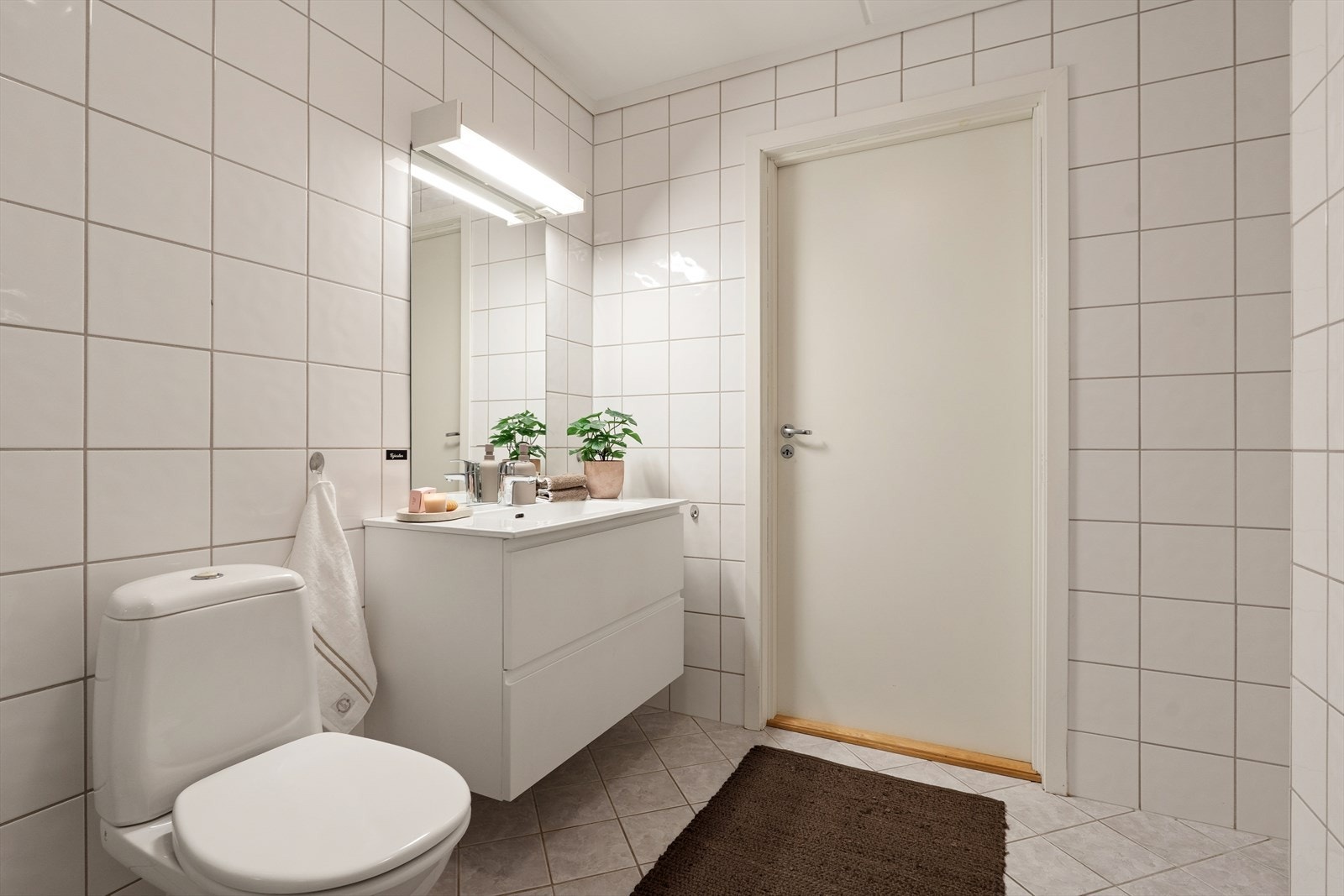 Rommet er utstyrt med dusjdører i glass, gulvmontert toalett, servantskap og har opplegg for vaskemaskin. Galleribilde