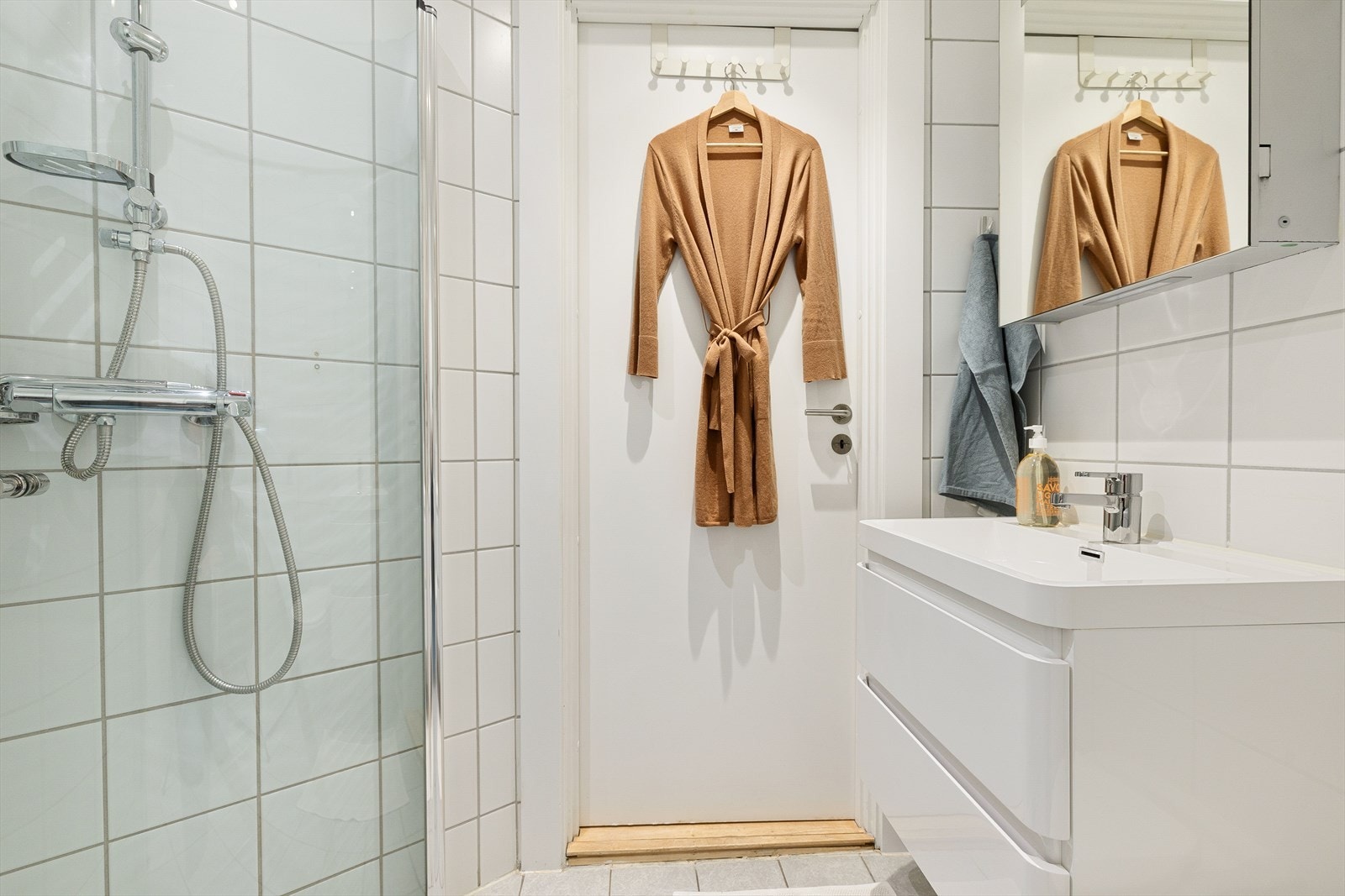 Ellers er badet med veggmontert klosett, servant med oppbevaring i underskap, dusj med innfellbare glassdører, samt opplegg for vaskemaskin. Galleribilde