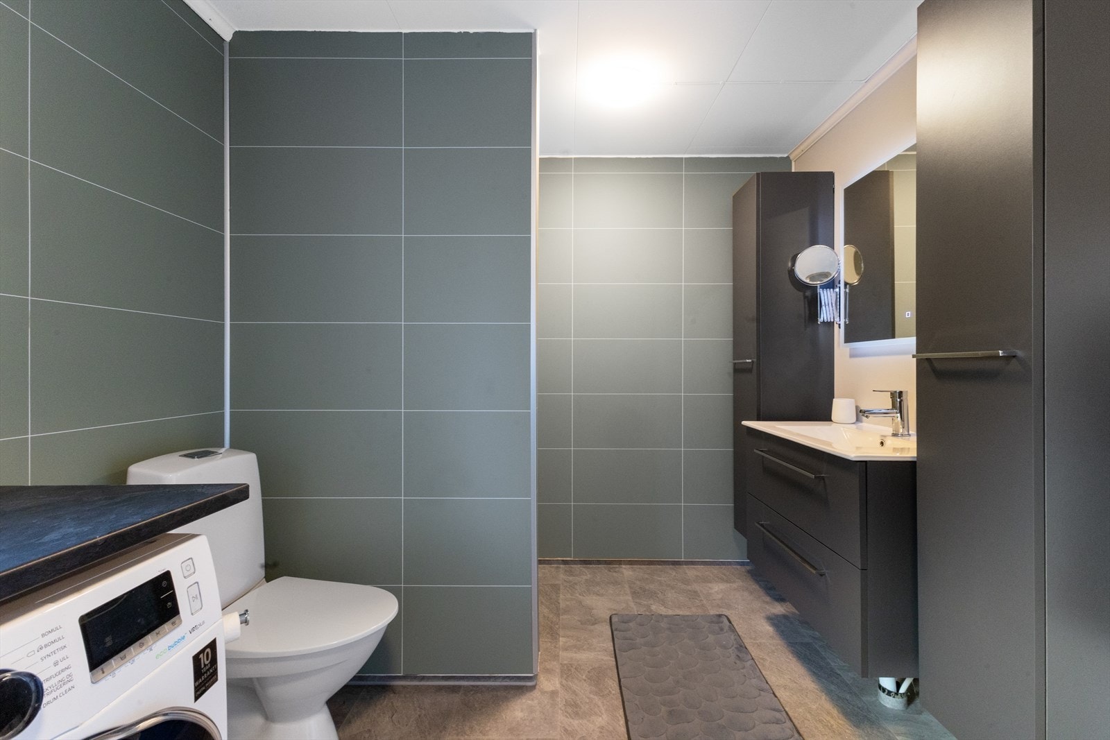 Bad/vaskerom ble pusset opp i 2021 og har vinylbelegg på gulv med termostatstyrte varmekabler og baderomsplater på vegger. Galleribilde