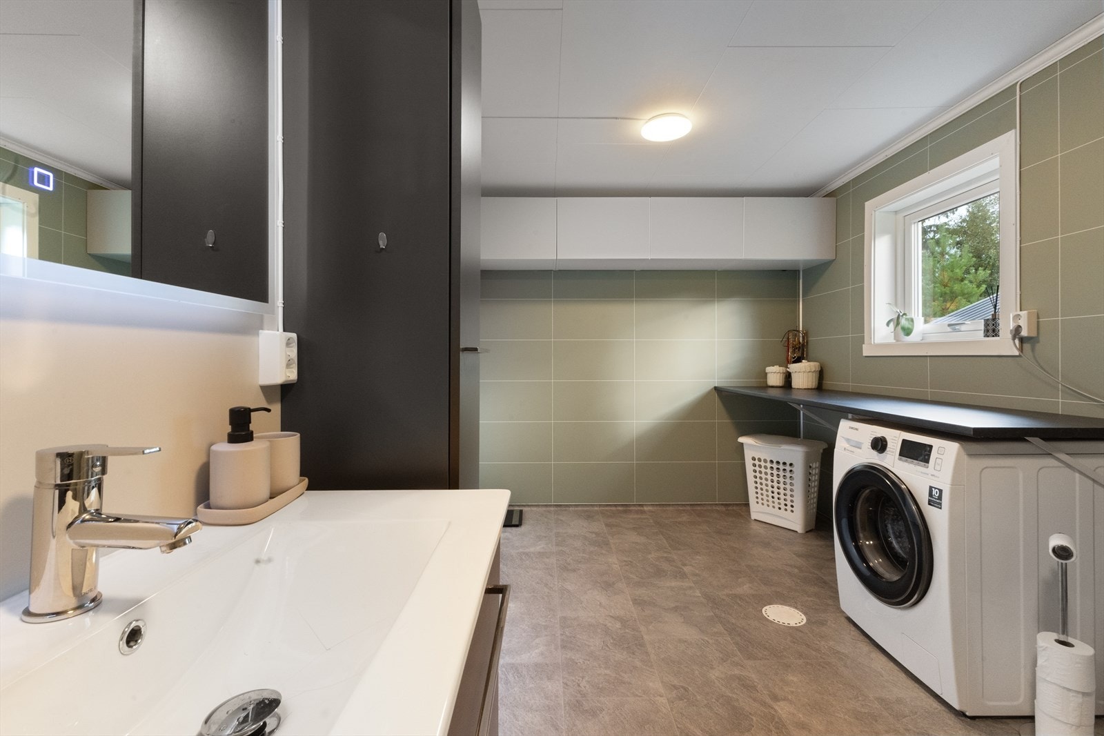 Badet har toalett, dusjnisje, opplegg for vaskemaskin og tørketrommel, og en romslig innredning med nedfelt servant. Galleribilde