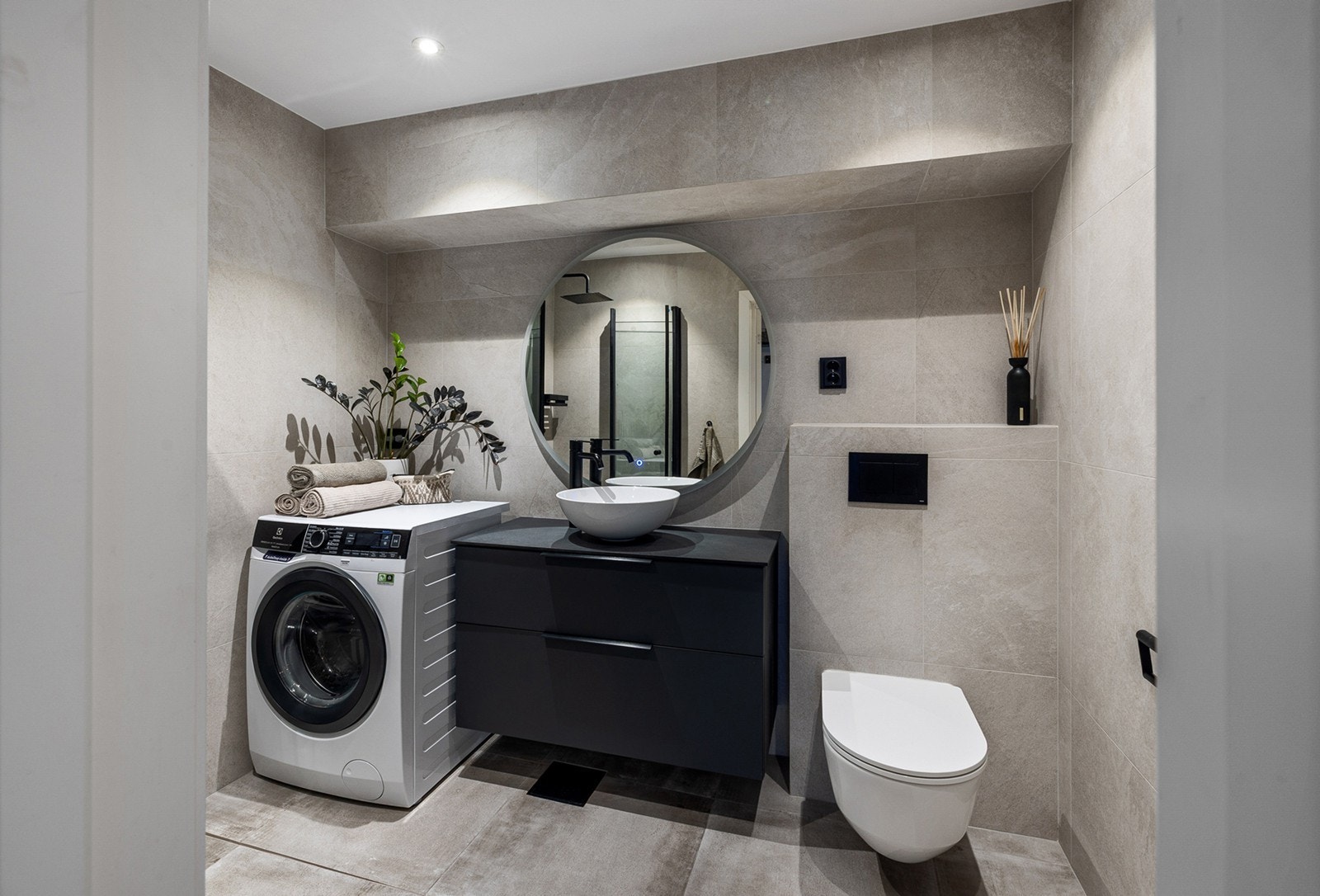 Badet har romslig dusjsone, praktisk opplegg for vaskemaskin og tidløs innredning med god oppbevaringsplass. Galleribilde