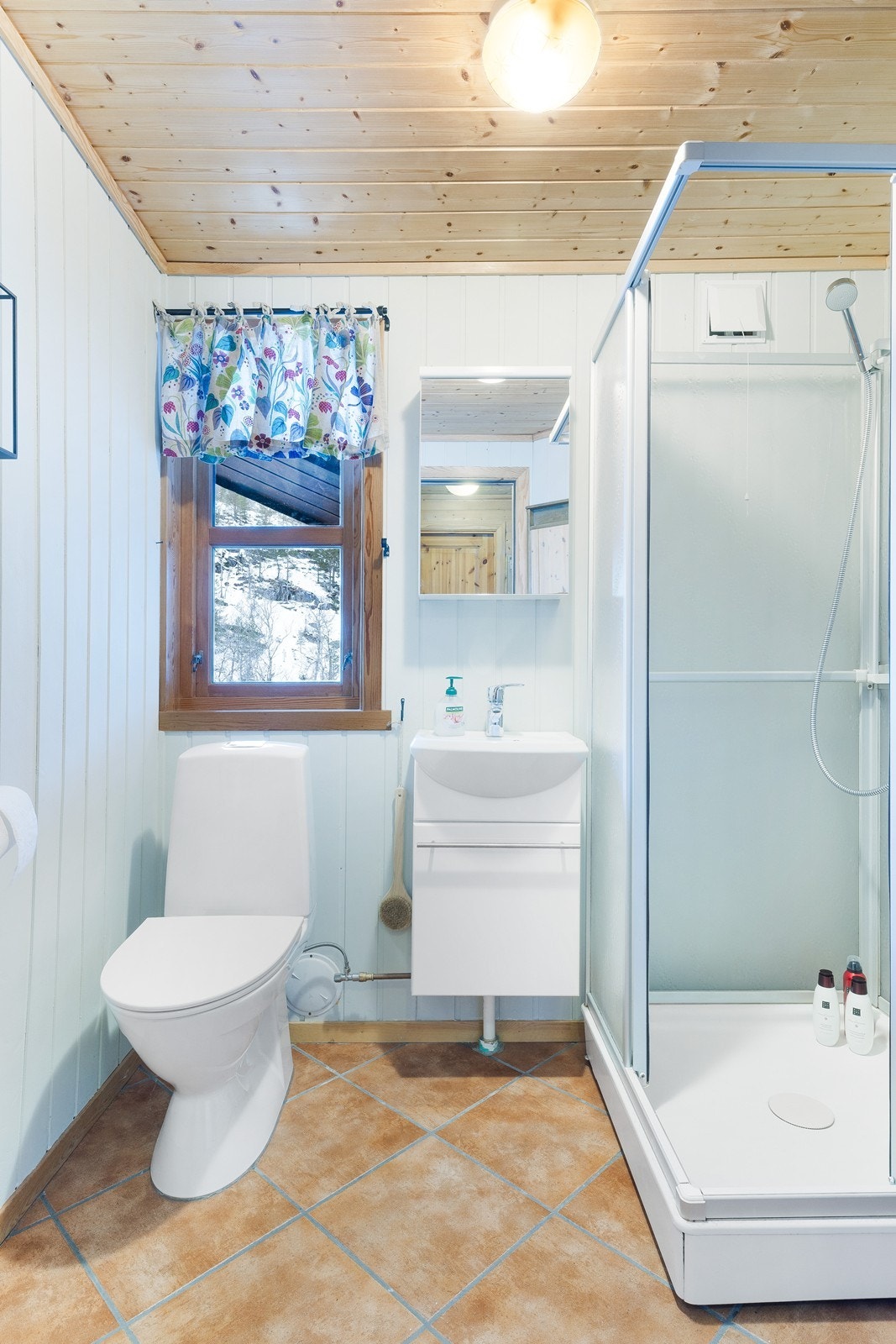 Baderommet har flislagt gulv med varmekabler og lyse panelte vegger. Galleribilde