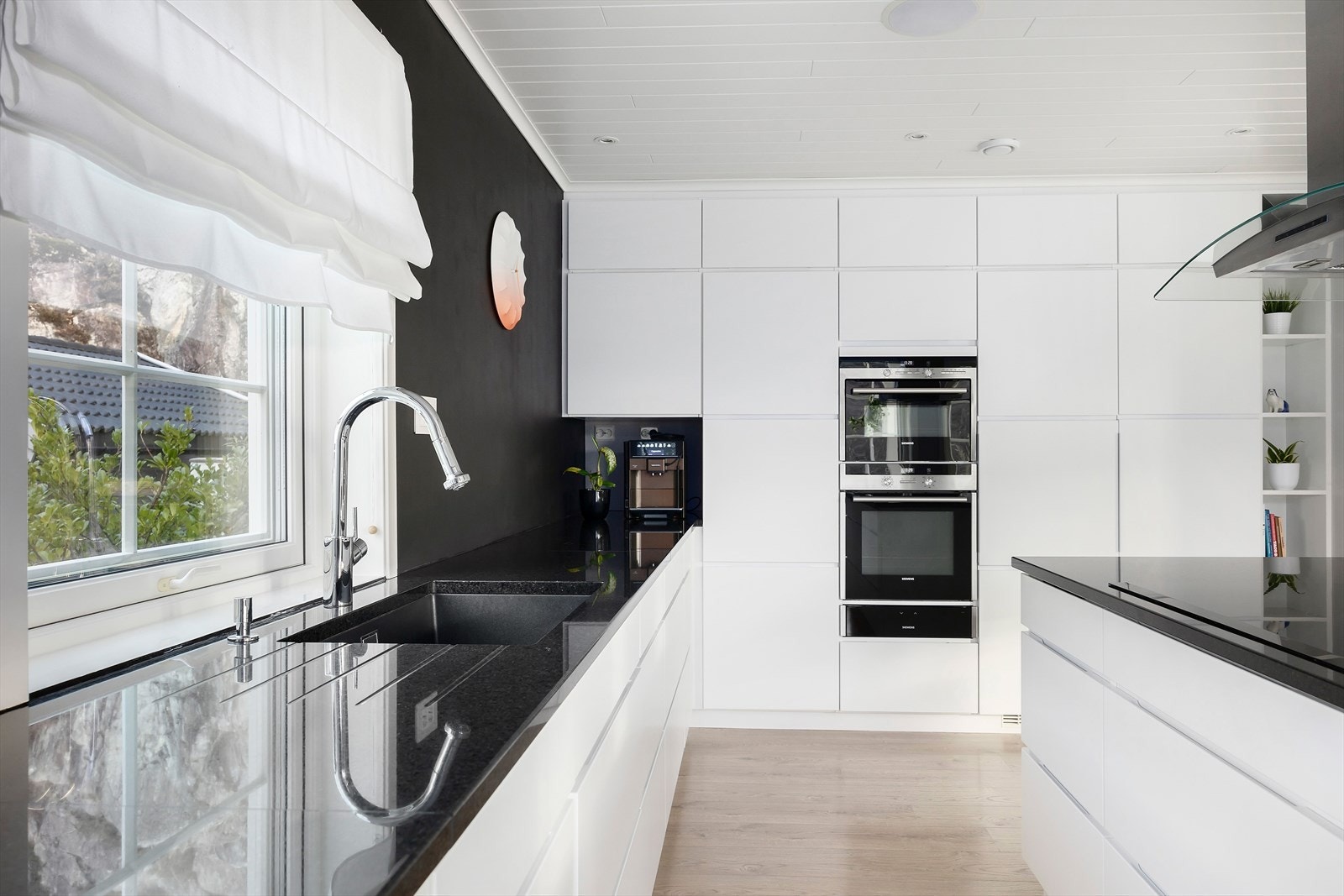 Kjøkkeninnredningen har slette fronter med integrert grep, kombinert med en elegant granittbenkeplate og underlimt vask. Galleribilde