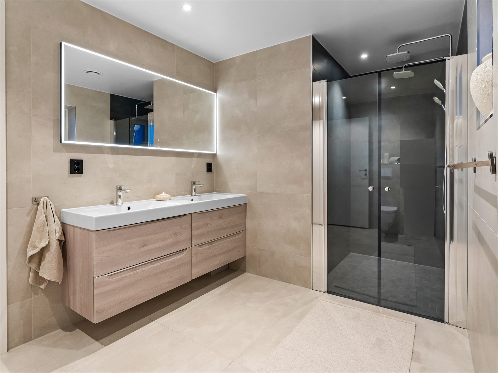 Badet holder høy standard med moderne fliser, stilren innredning og dobbel regnfallsdusj. Galleribilde