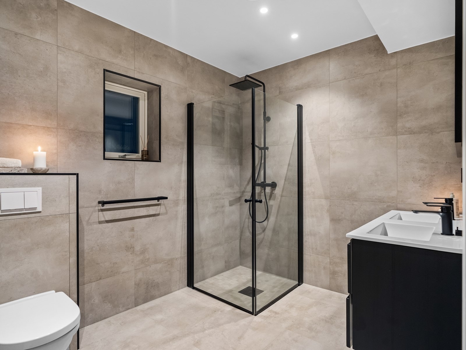 Lekkert baderom med rene linjer og delikate fliser. Det er dobbel servant med underskuffer, dusjhjørne med innfellbare glassdører, speil med belysning og vegghengt totalett. Galleribilde