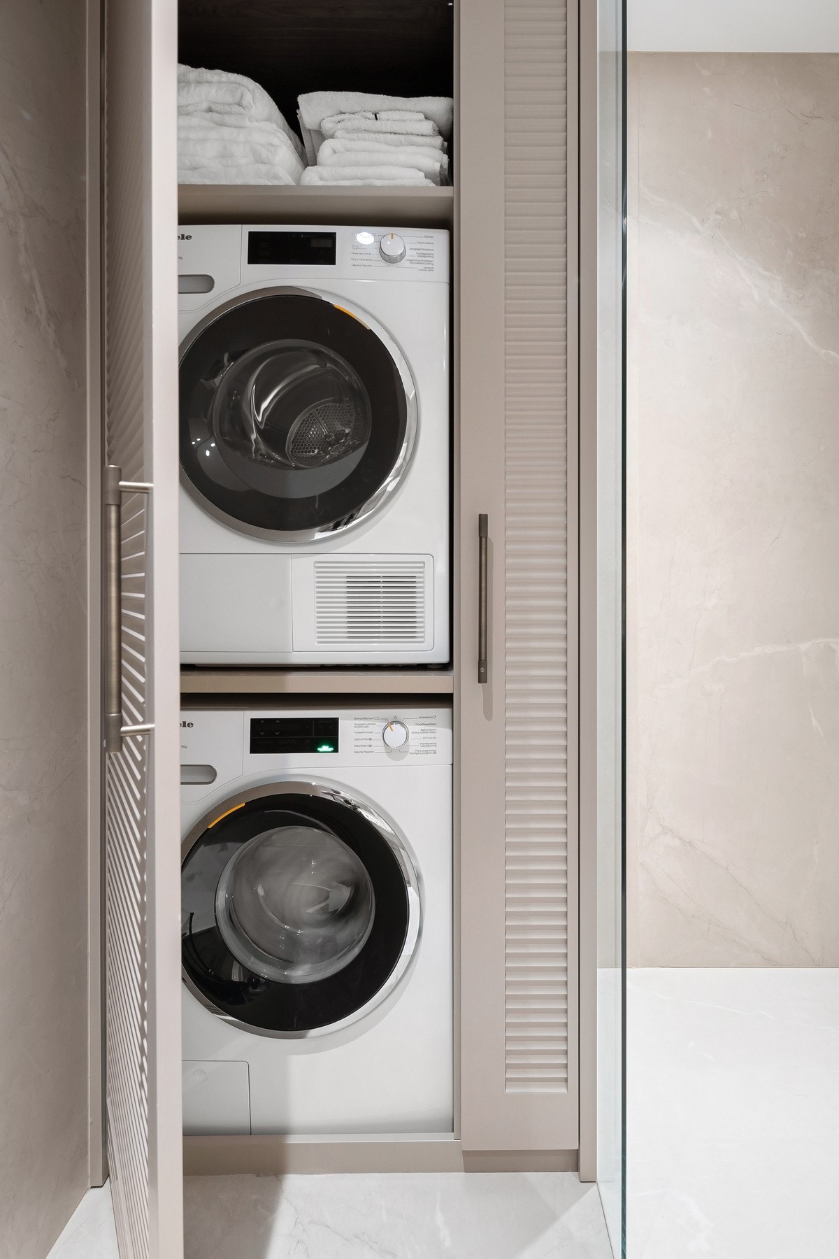 Vaskemaskin og tørketrommel praktisk plassert og skjermet i skap. Galleribilde