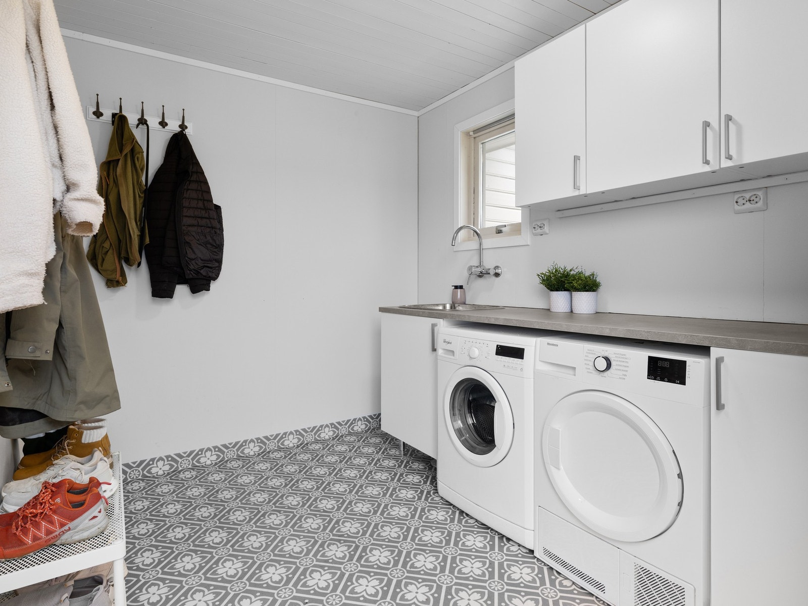 Vaskerommet er en funksjonell og romslig plass som gjør hverdagslige gjøremål lettere og mer effektive. Her finner du benkeplass til sortering og folding av klær, samt praktisk oppbevaringsplass for vaskemidler og annet utstyr. God plass til både vaskemas Galleribilde