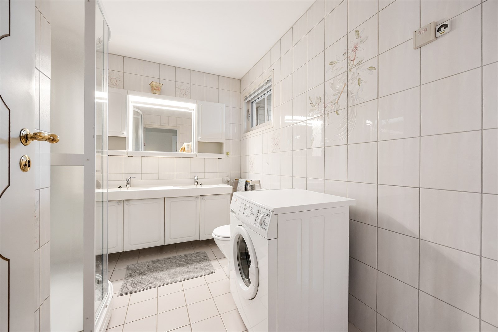 Etasjens bad er helfliset og utstyrt med dusjkabinett og opplegg for vaskemaskin. Galleribilde