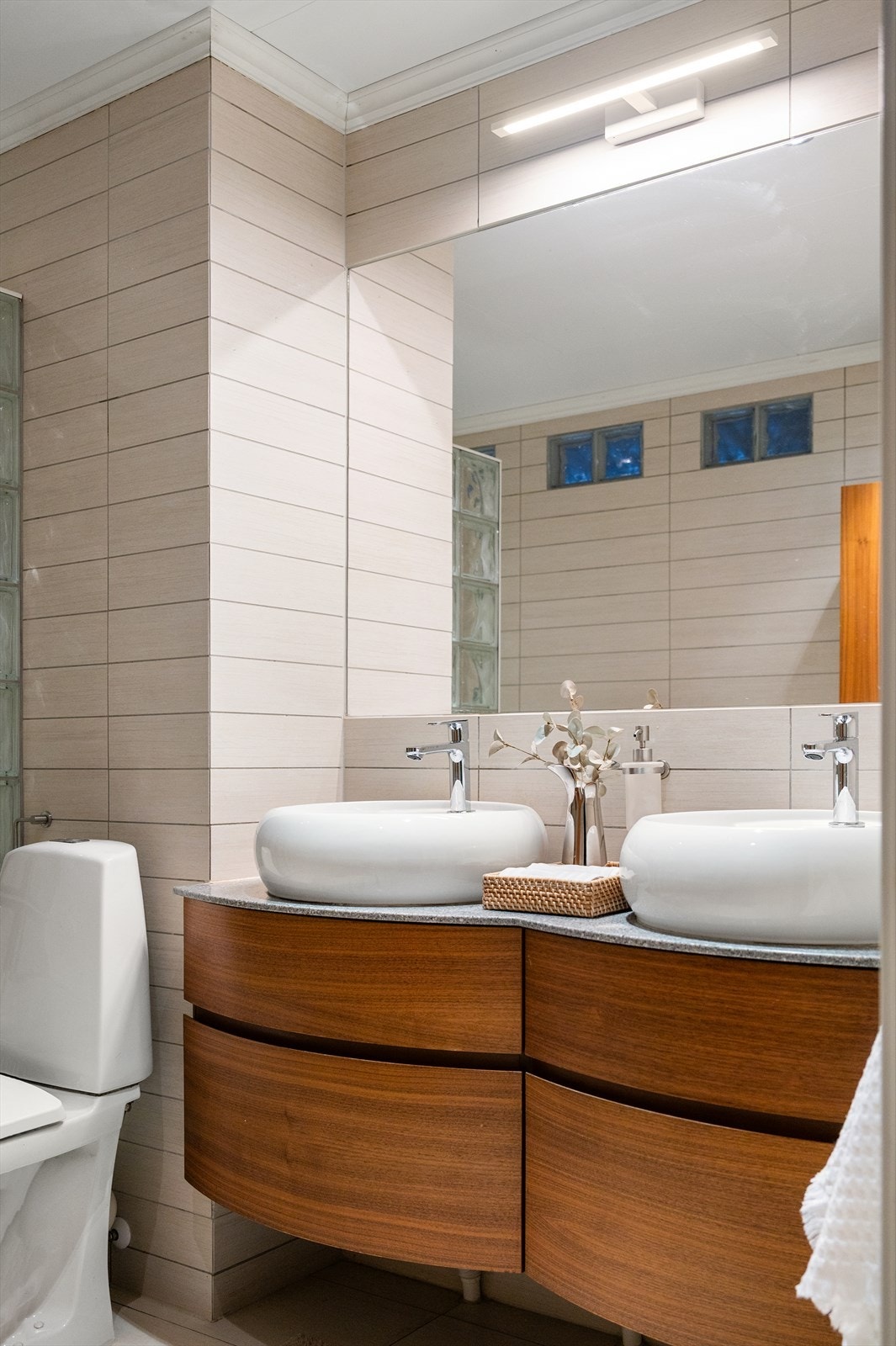 Delikat bad med dobbel servant og moderne innredning i varme toner. Galleribilde